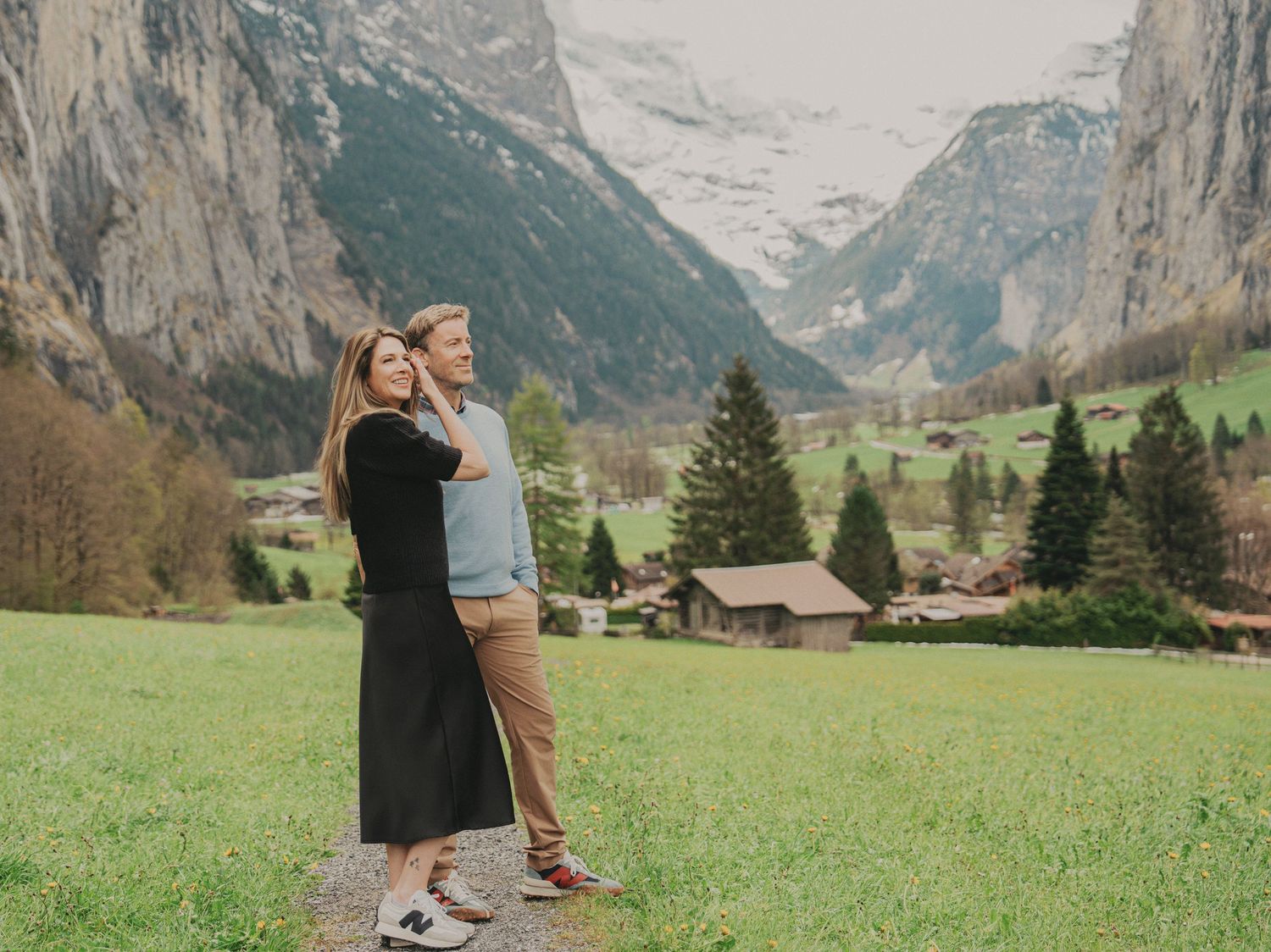 Romantic couple embracing on mountain path gazing at scenic Lauterbrunnen valley in Switzerland.