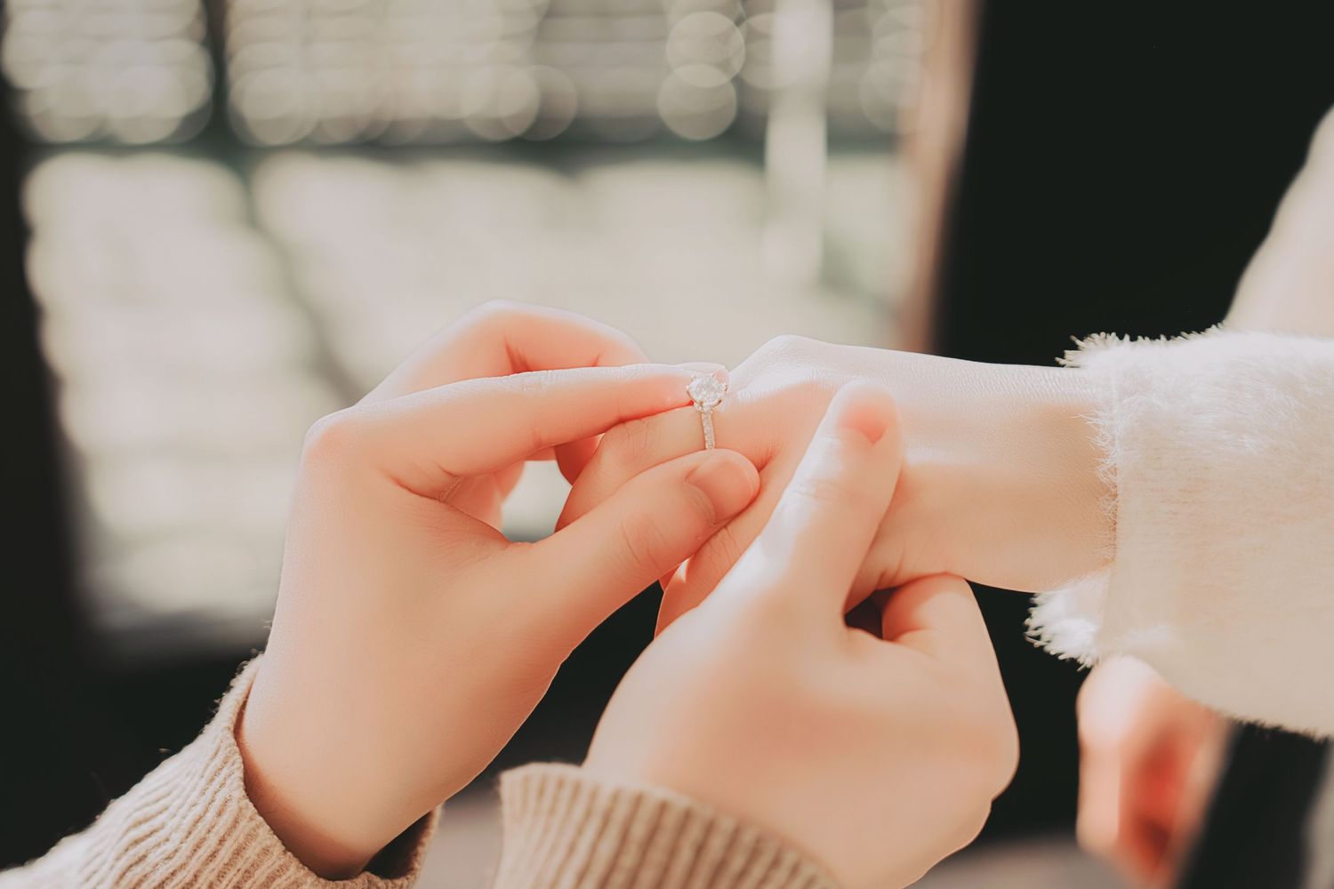 Close-up of a man sliding a delicate diamond engagement ring onto a woman's finger during a proposal.
