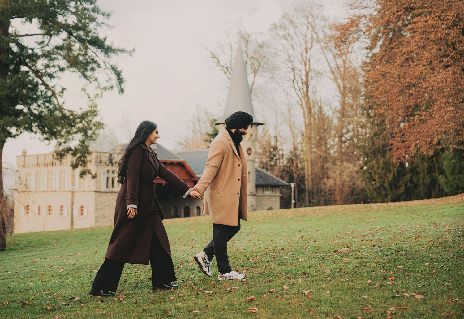 Couple walking hand in hand through colorful autumn park landscape.