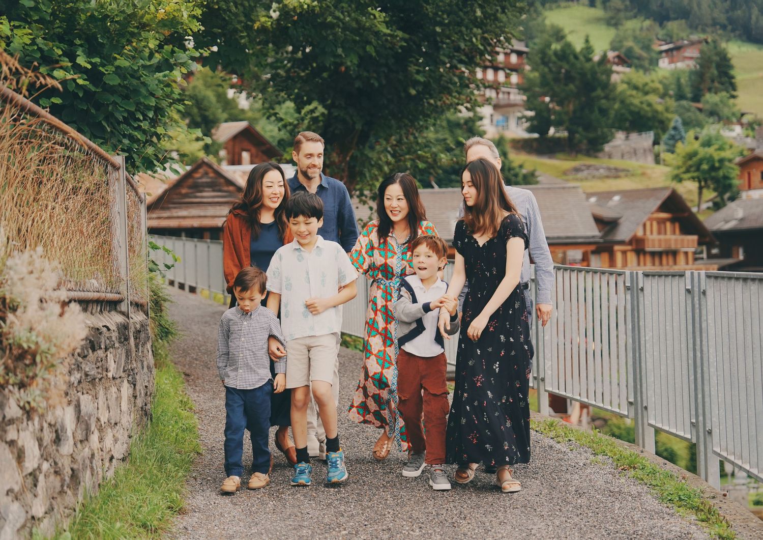 A multigenerational family strolls together along a charming Swiss alpine village pathway.