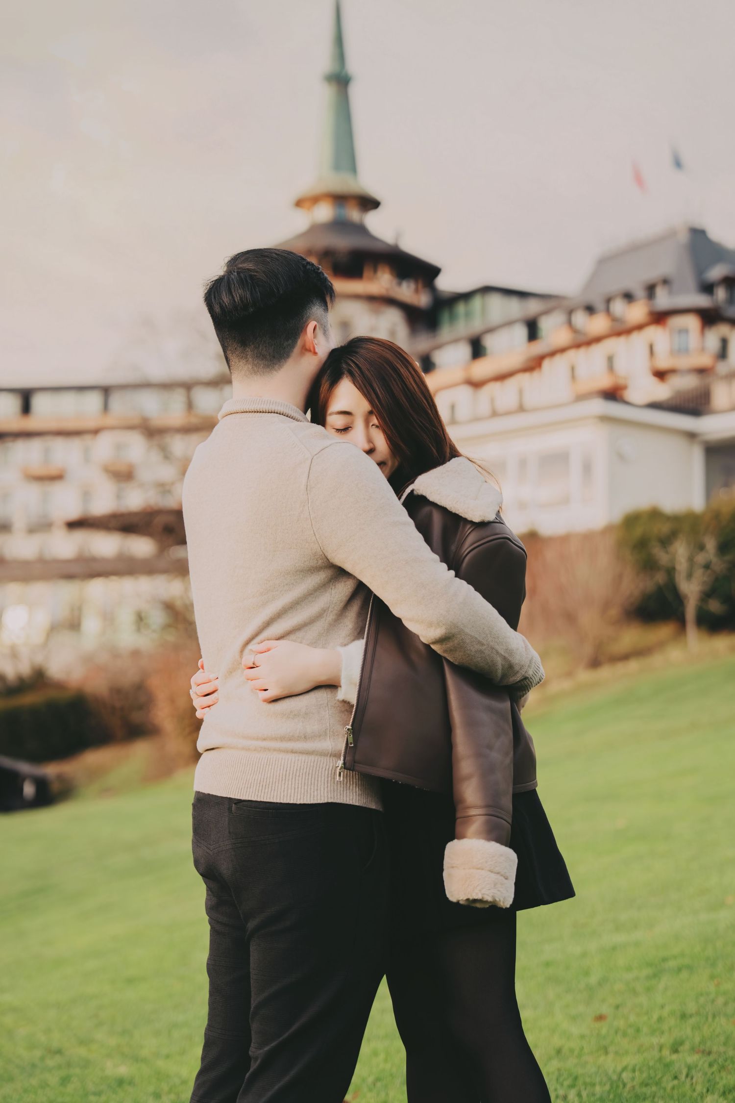 Couple sharing a warm embrace outdoors near a grand European-style building.