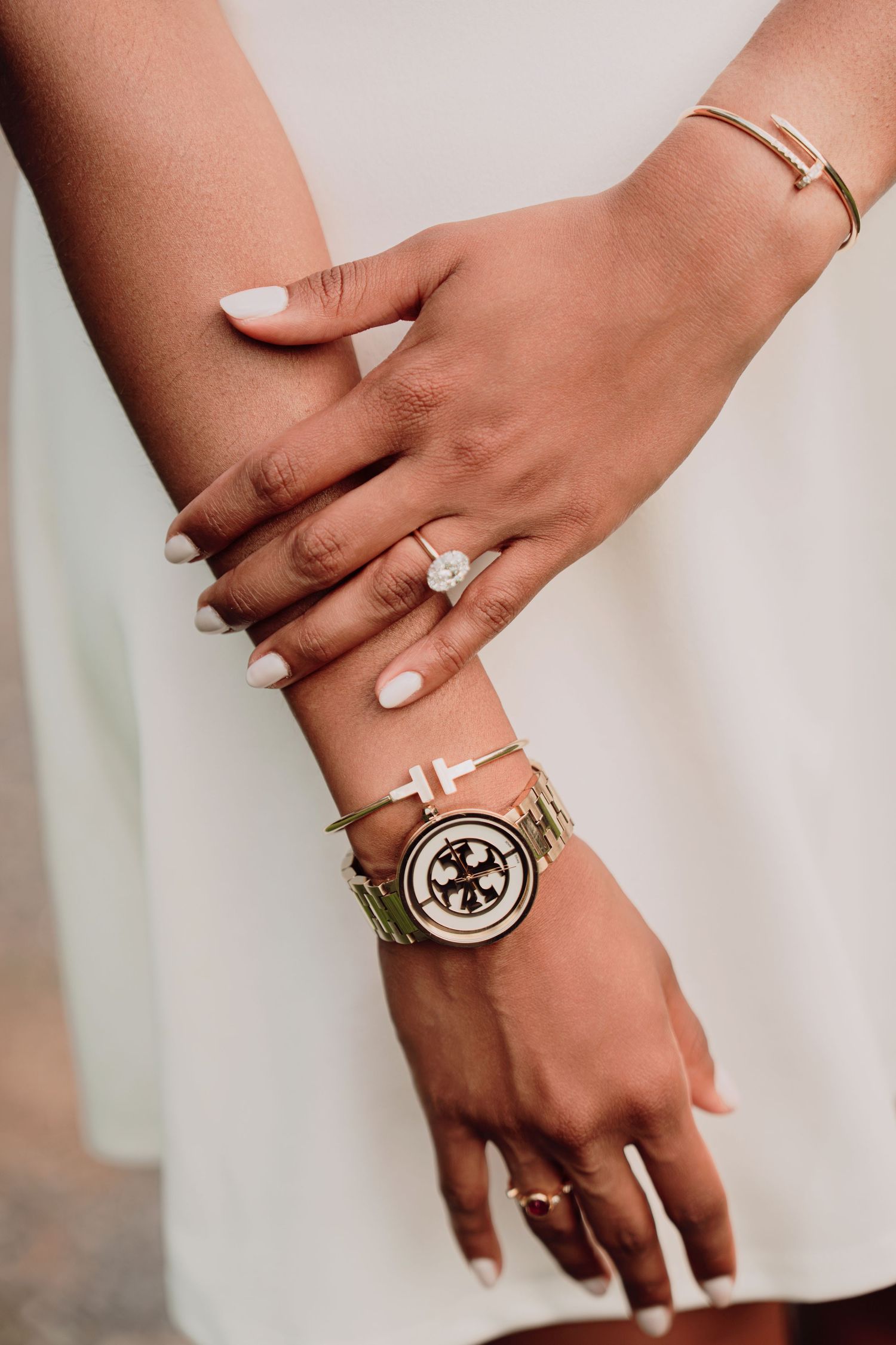 Close-up of a bride's hands showing a diamond engagement ring, gold bracelet, and luxury watch.