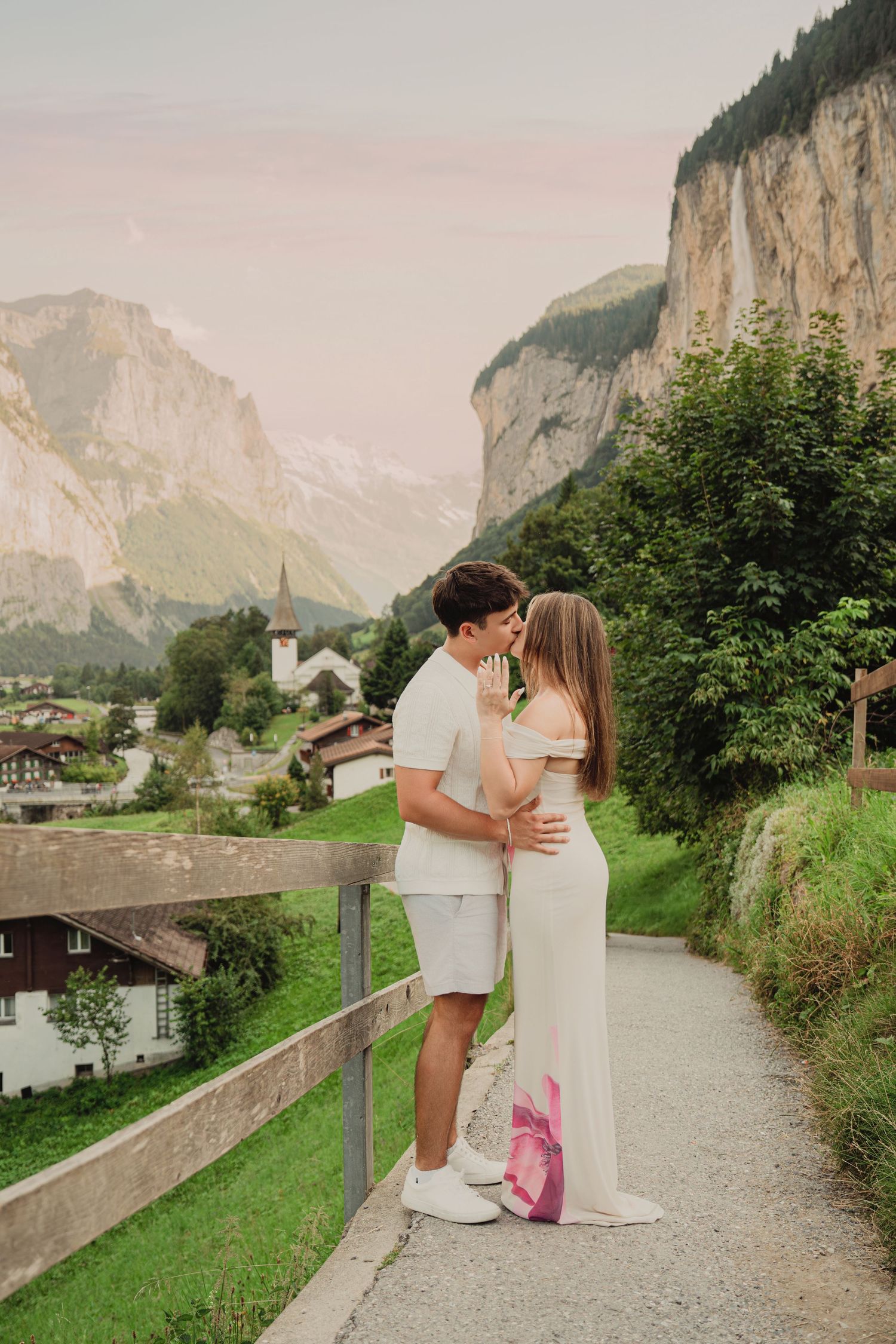 Couple embracing on scenic Lauterbrunnen village pathway at dusk with Swiss mountain backdrop.