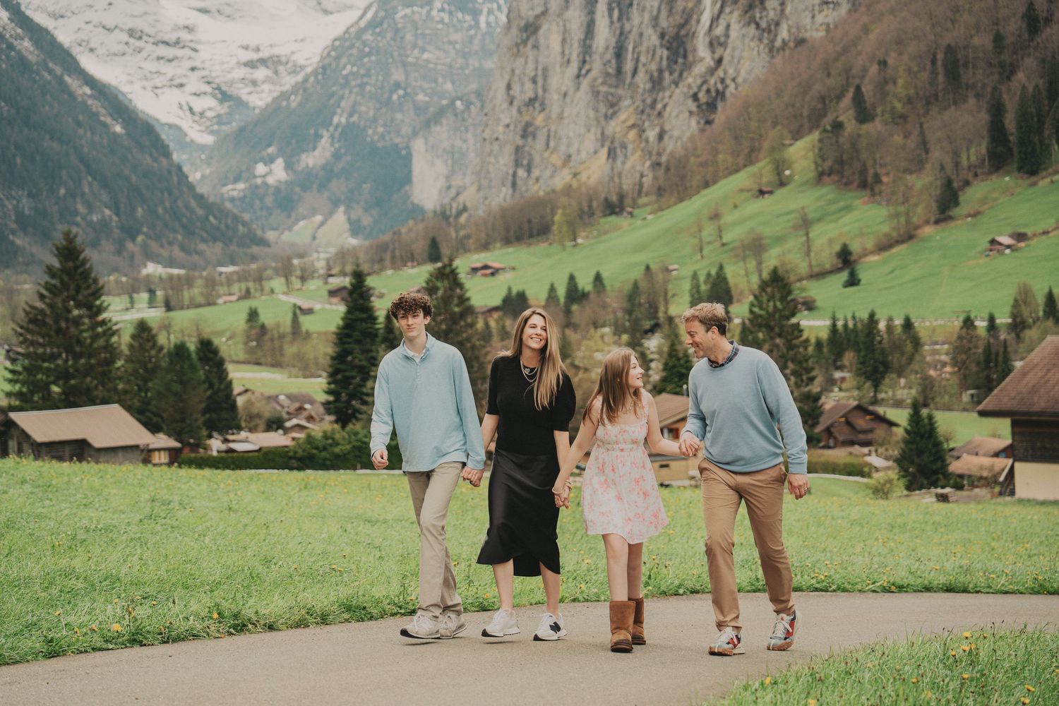 Family strolling together on a path through the beautiful green valley of Lauterbrunnen, Switzerland.