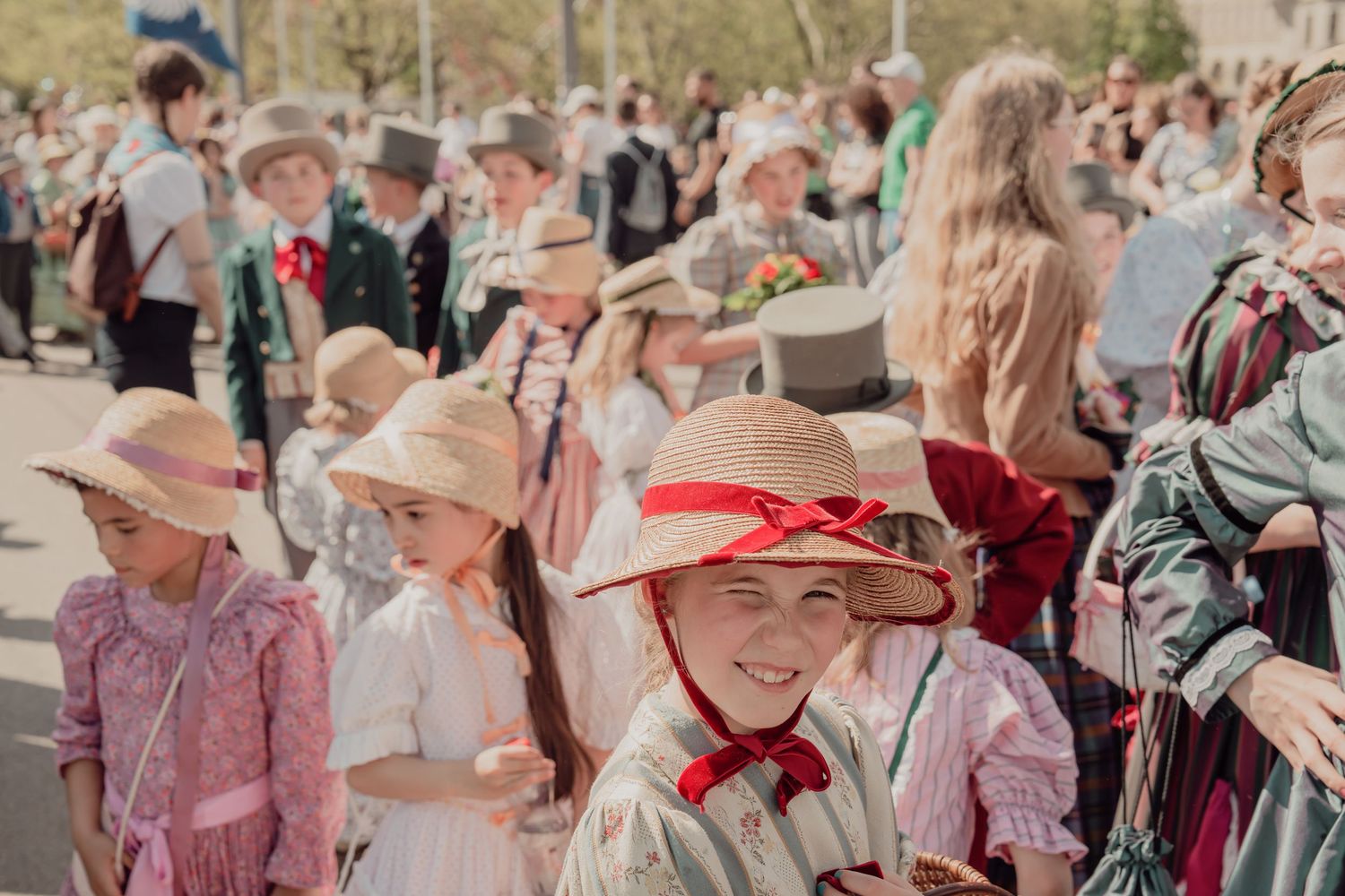 Smiling children in straw hats and vintage costumes gather at a colorful traditional Swiss festival parade.