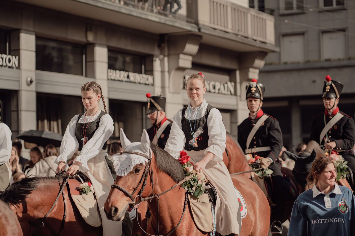 Women in traditional folk costumes ride horses during a colorful historical street parade in the city.