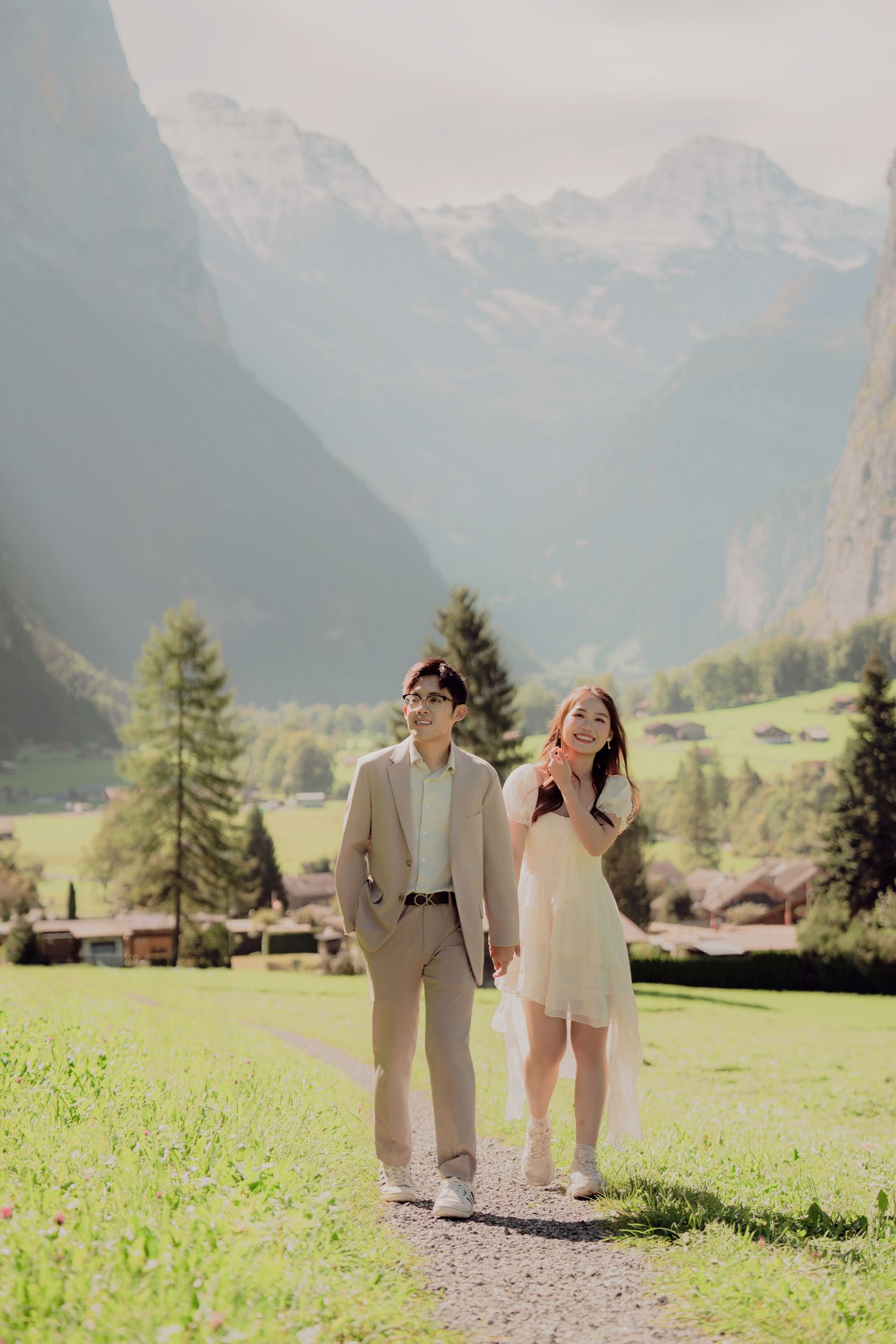 Couple walking hand in hand on a path through a lush Swiss Alpine valley.