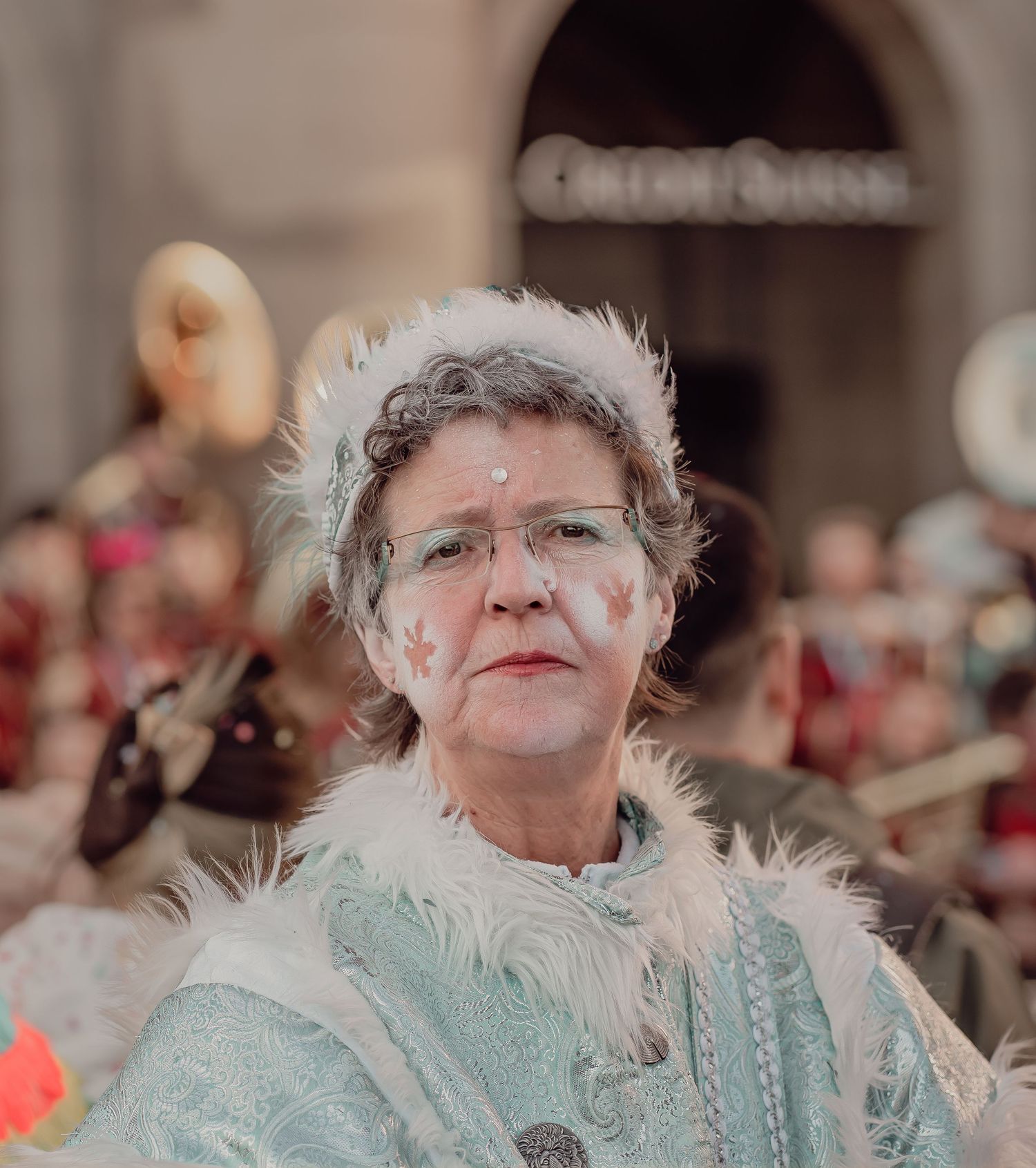 A woman in a white fur-trimmed winter costume with face paint at a festive parade.