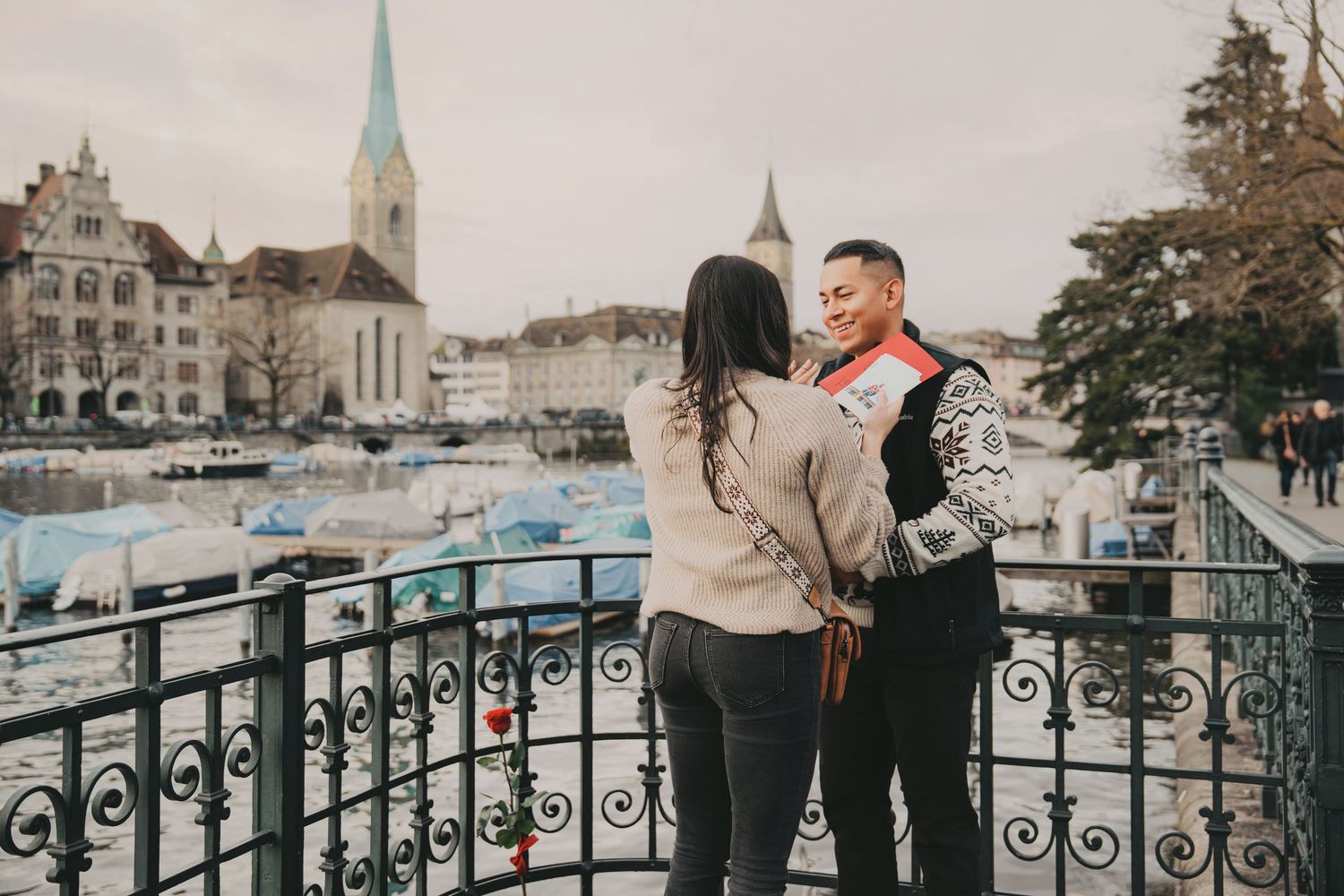 Happy couple sharing a tender moment on ornate bridge overlooking Zurich waterfront.