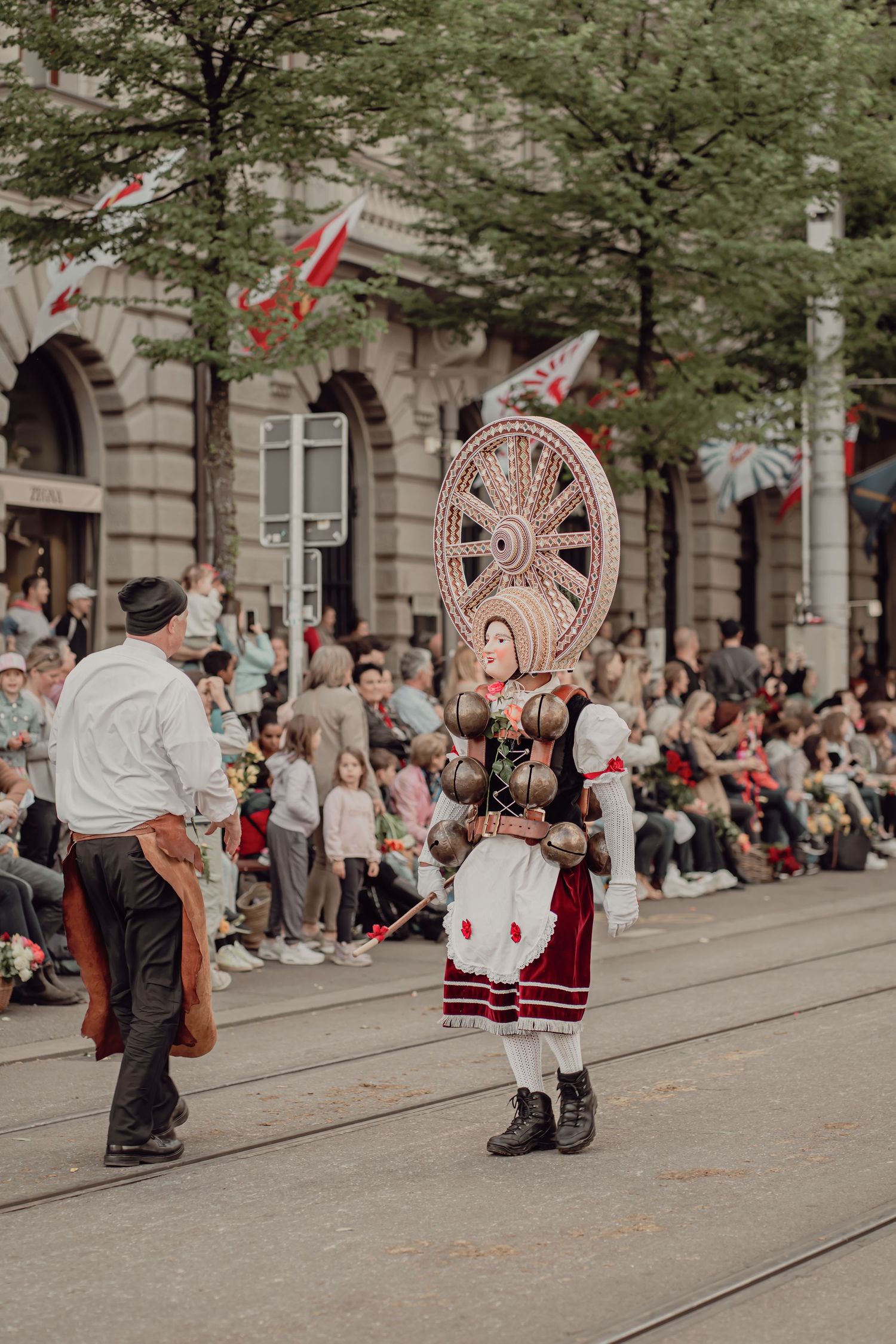 Woman in traditional folk costume balancing large decorative spinning wheel headdress.