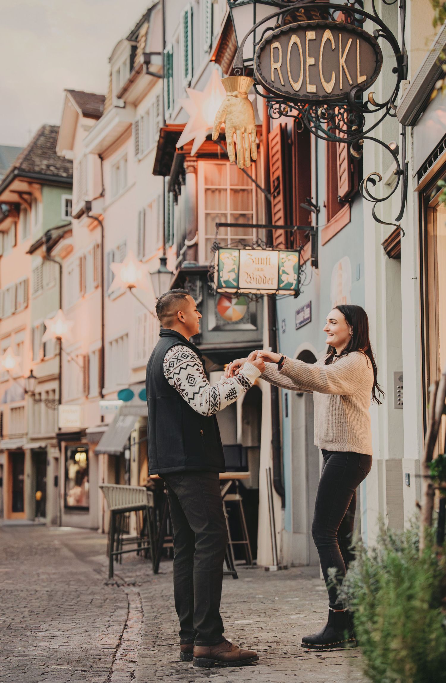 Happy couple holding hands and dancing on a charming European cobblestone street in Zurich.