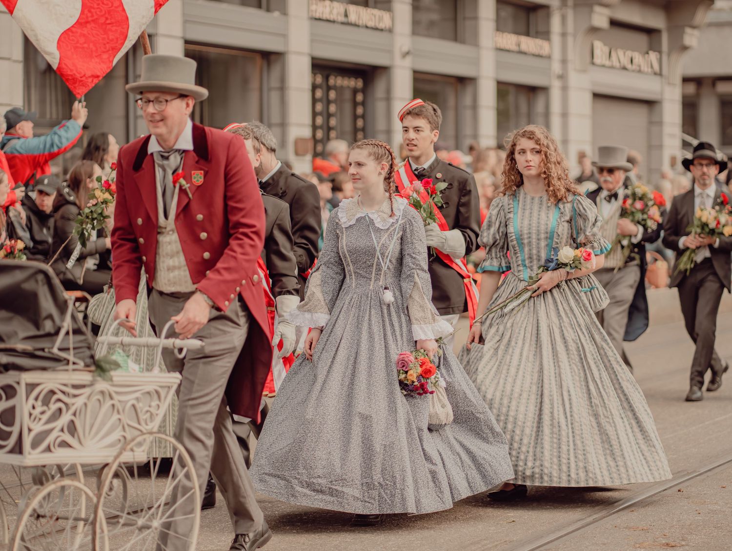 People in Victorian-era costumes marching in a colorful street parade.
