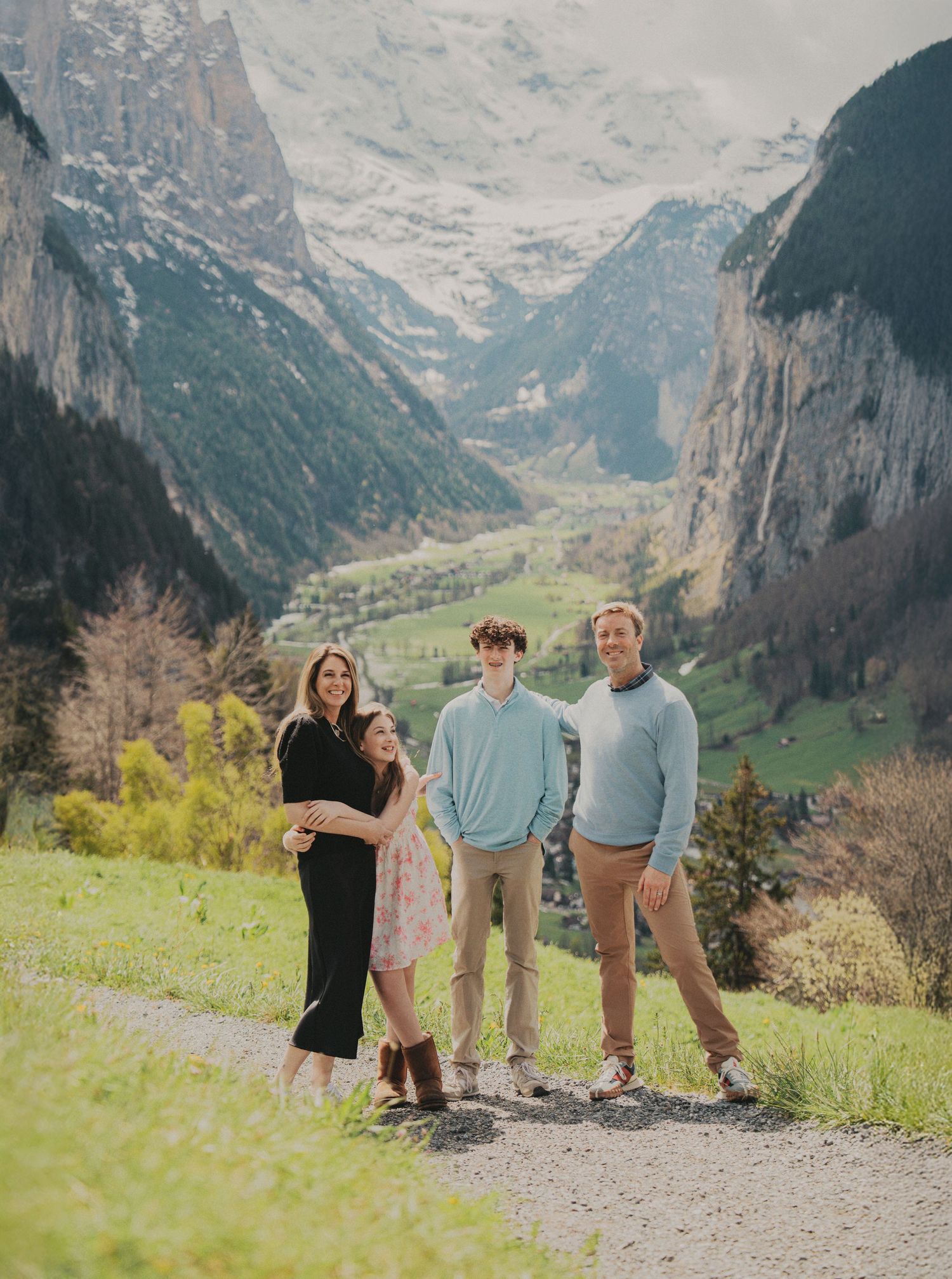 Family portrait on a gravel path with breathtaking Lauterbrunnen valley and mountains behind.