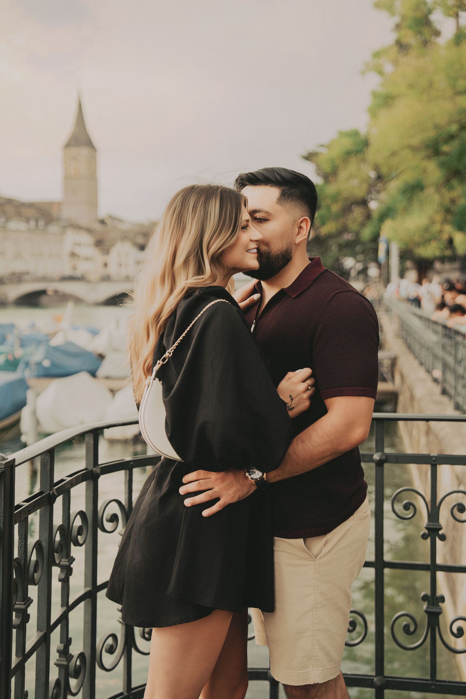 Romantic couple sharing a kiss on a decorative iron balcony along the Zurich riverside.