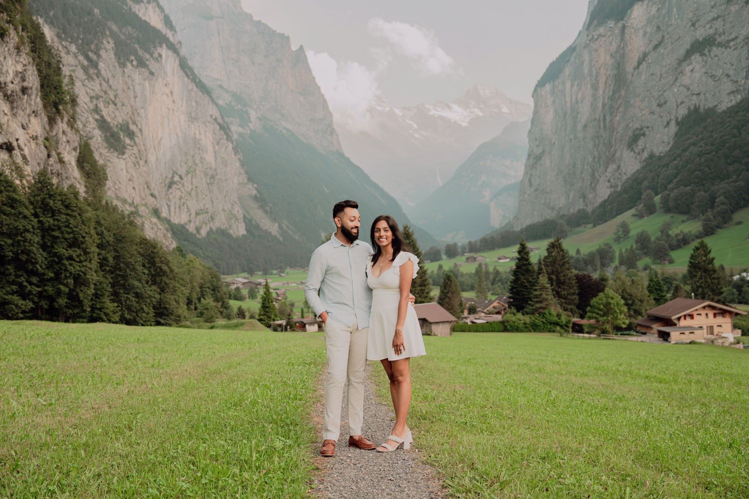 Couple standing together on a path in a breathtaking Swiss Alpine valley with towering rocky mountains.