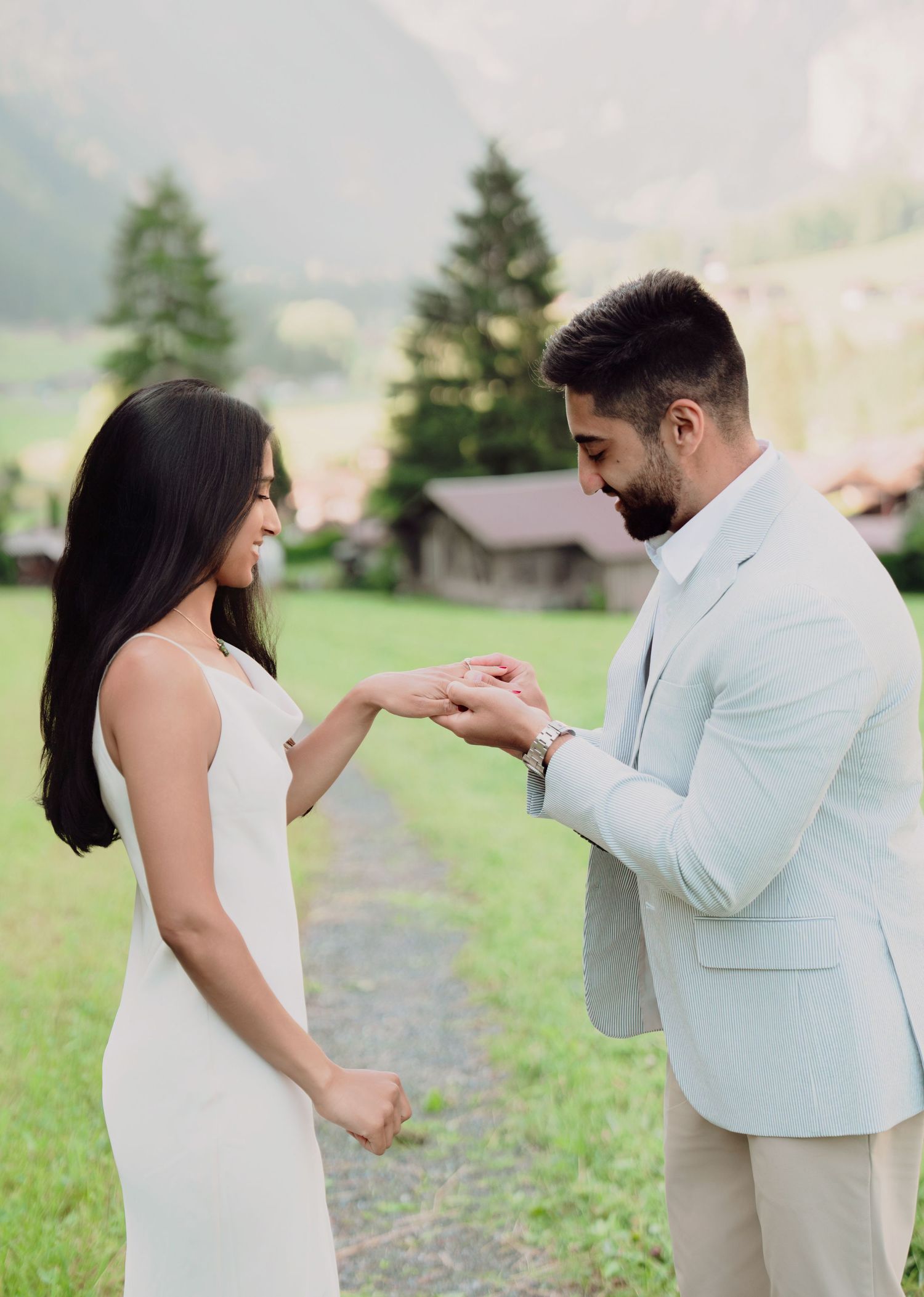 Groom placing ring on bride's finger during intimate outdoor ceremony in Swiss Alpine setting.