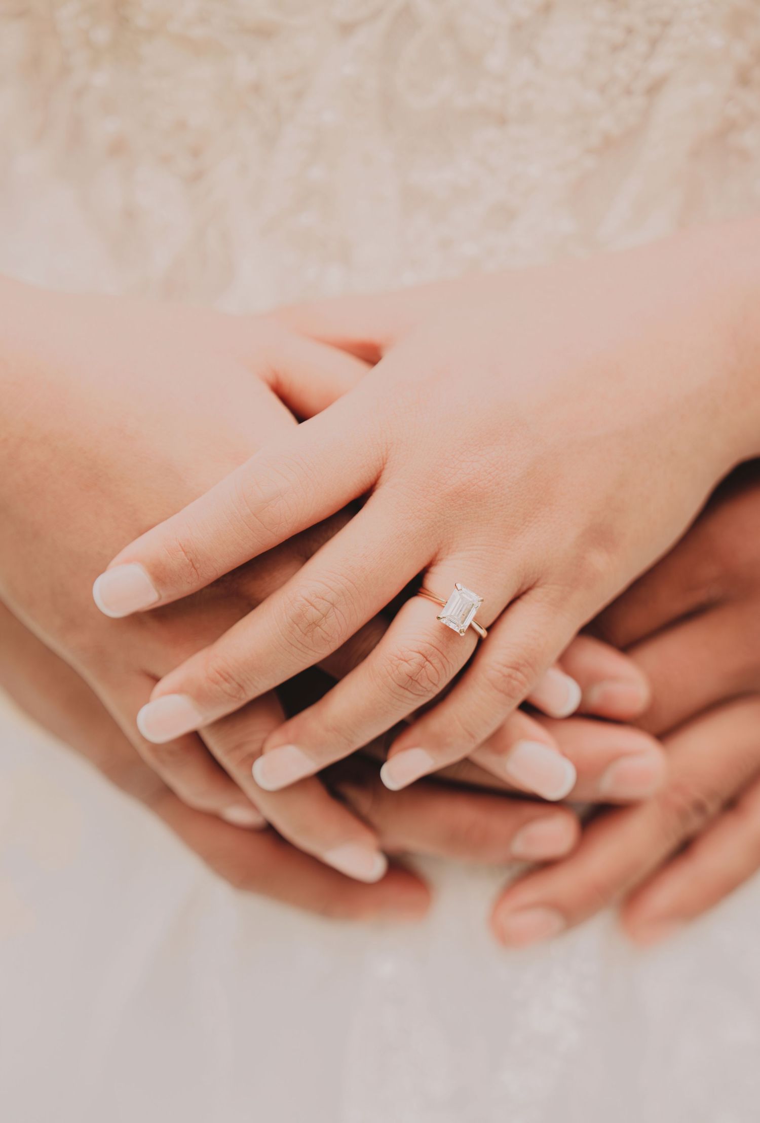 Close-up of bride's hand featuring stunning emerald-cut diamond engagement ring on wedding day.