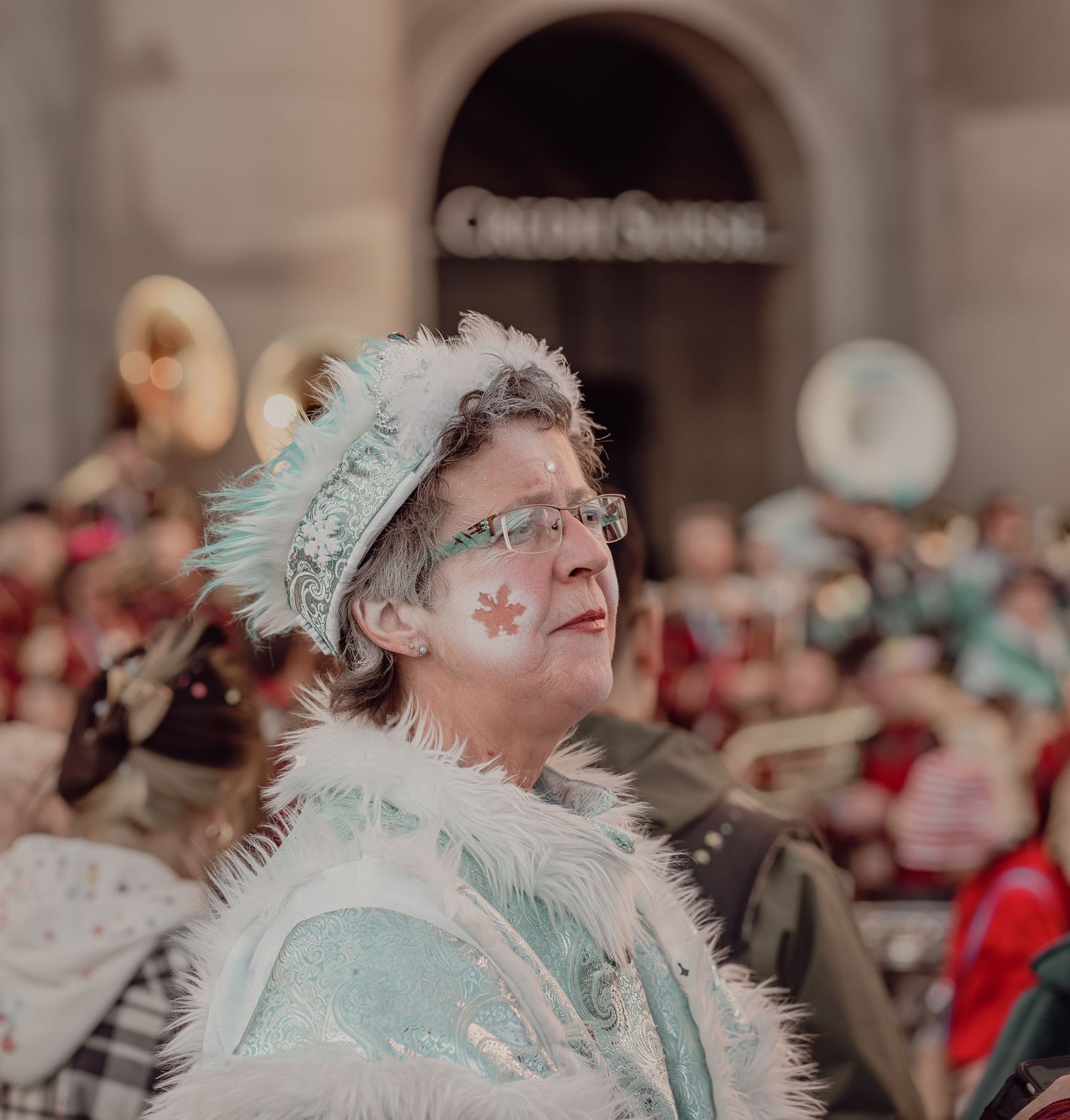 Woman in elegant light blue carnival costume with floral face paint at a festive parade.