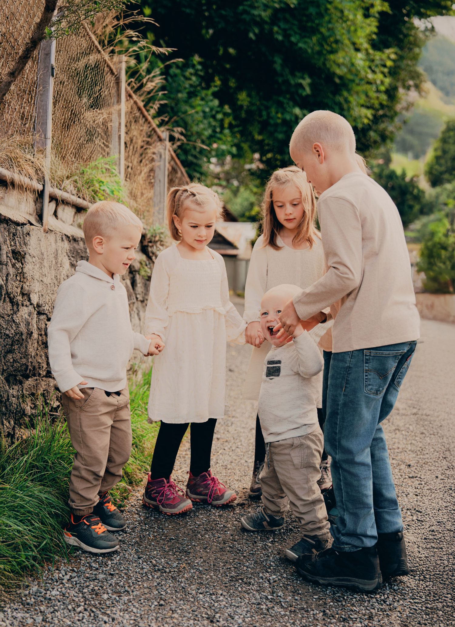 A father interacts warmly with three young children on a scenic alpine village pathway.