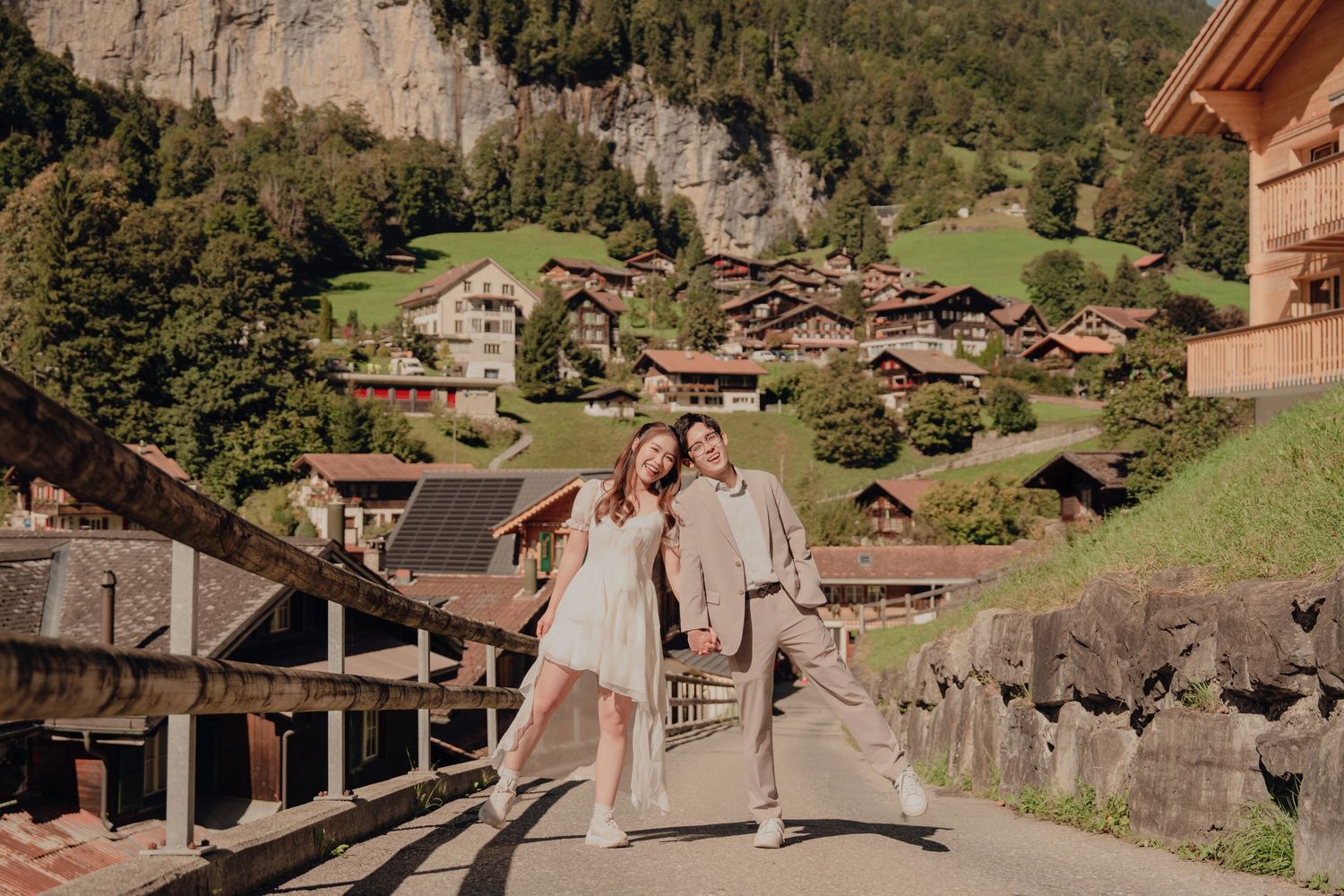 Joyful couple posing playfully on a bridge with charming Swiss chalet village backdrop in Lauterbrunnen.