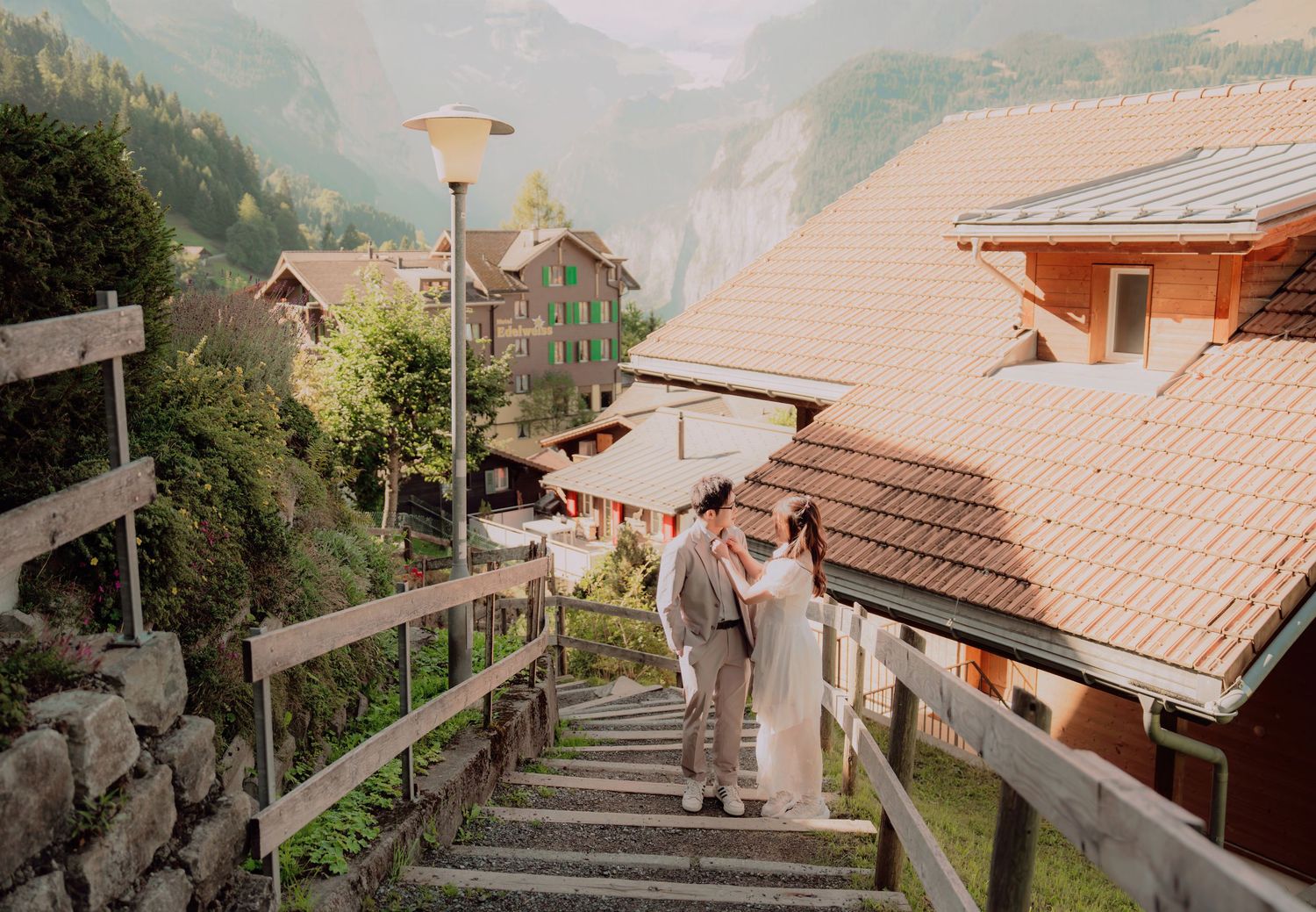 Bride and groom sharing intimate moment on wooden staircase in charming Swiss alpine village setting.