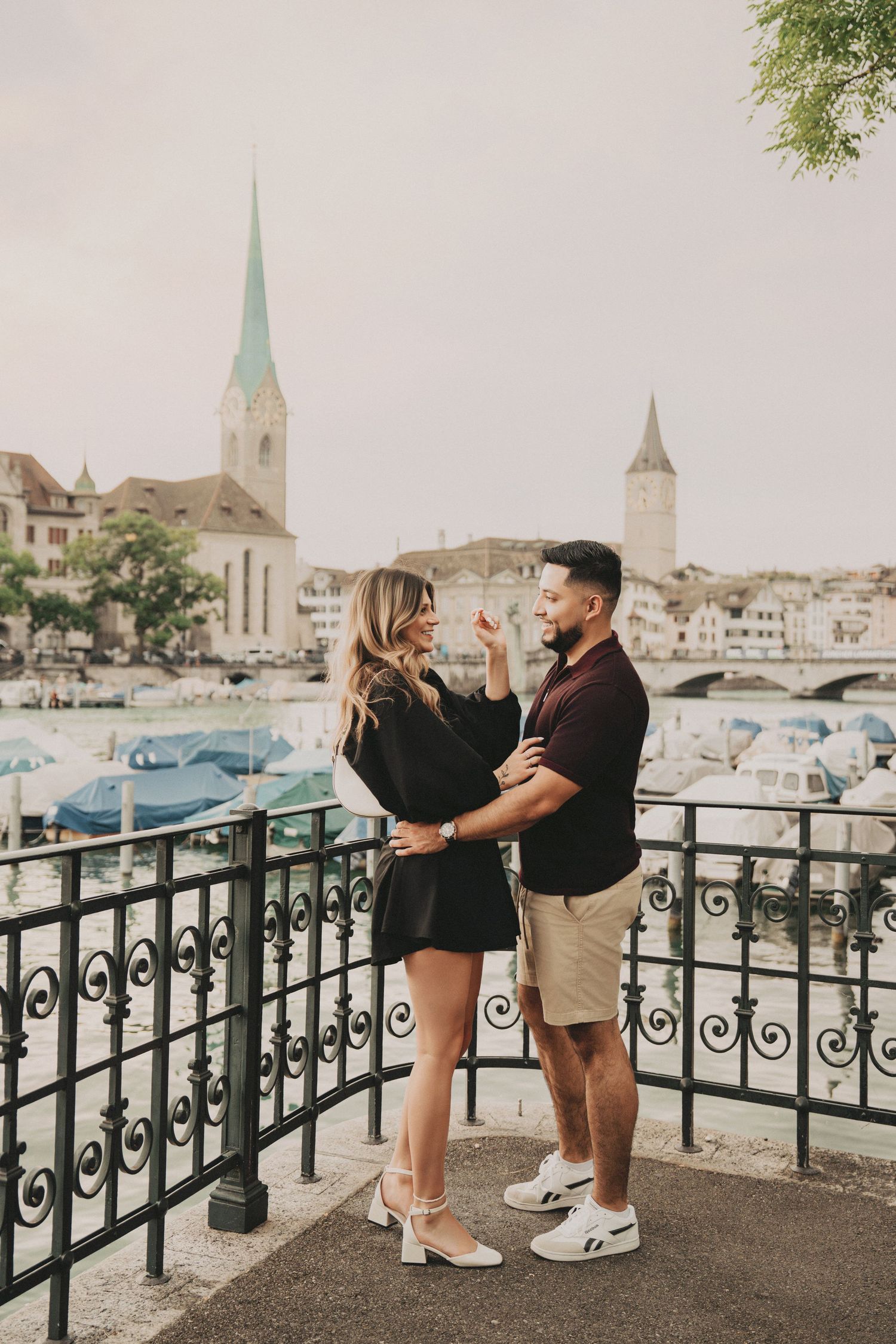 Couple embracing and laughing together on an ornate balcony overlooking the Zurich riverside.