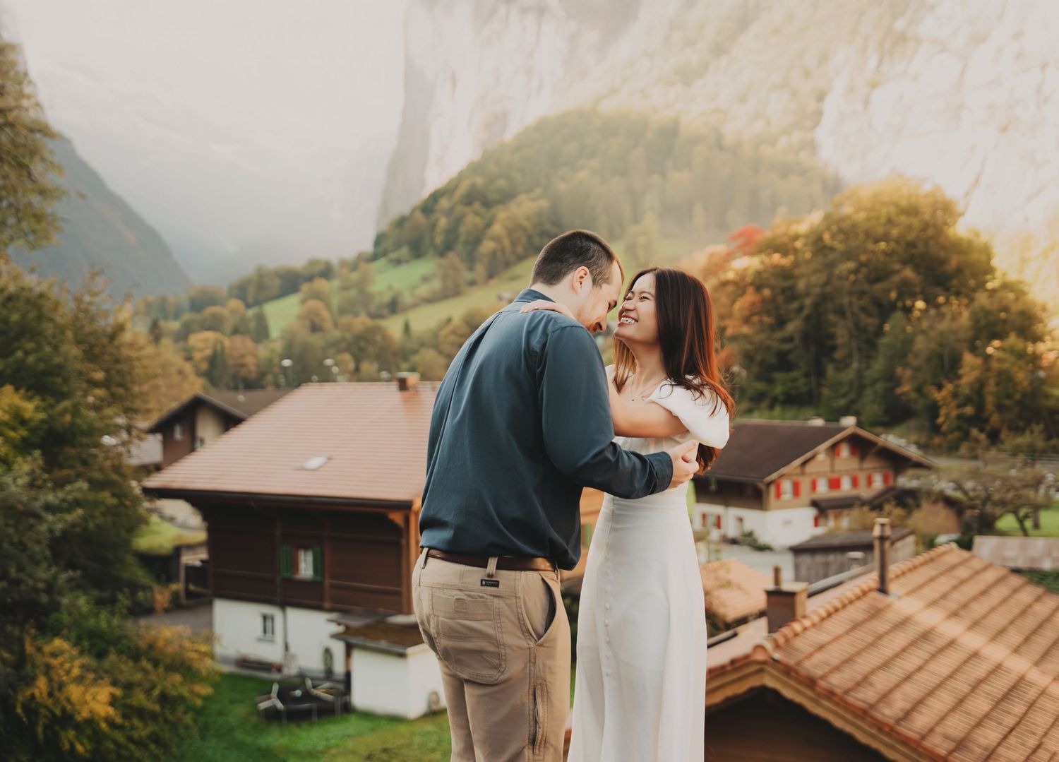 Happy couple dancing together with Swiss alpine village and mountains behind them.