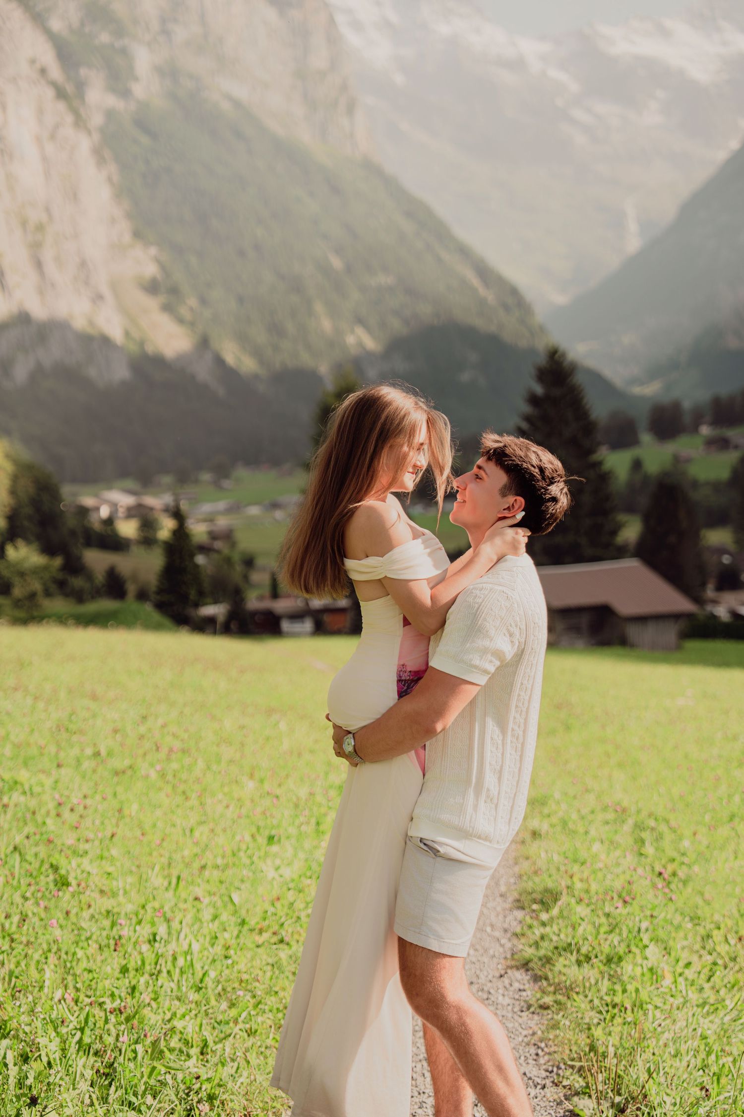 Couple sharing a romantic moment on a path in Lauterbrunnen valley with lush green Swiss Alps.