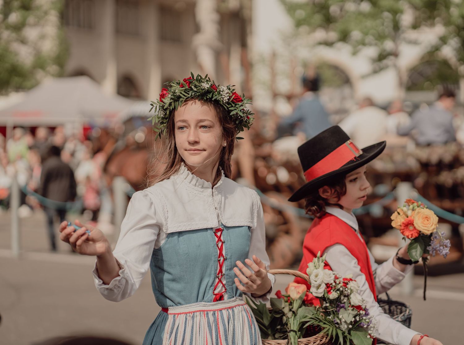 Young woman in traditional Swiss folk costume wearing a floral wreath crown at a cultural parade.