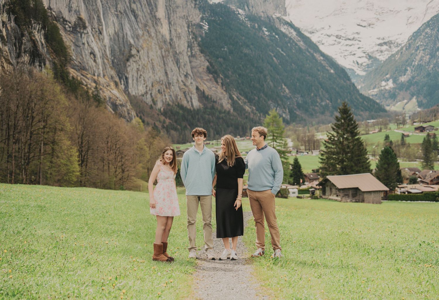 Family of four standing on mountain path in Lauterbrunnen valley Switzerland with scenic alpine views.