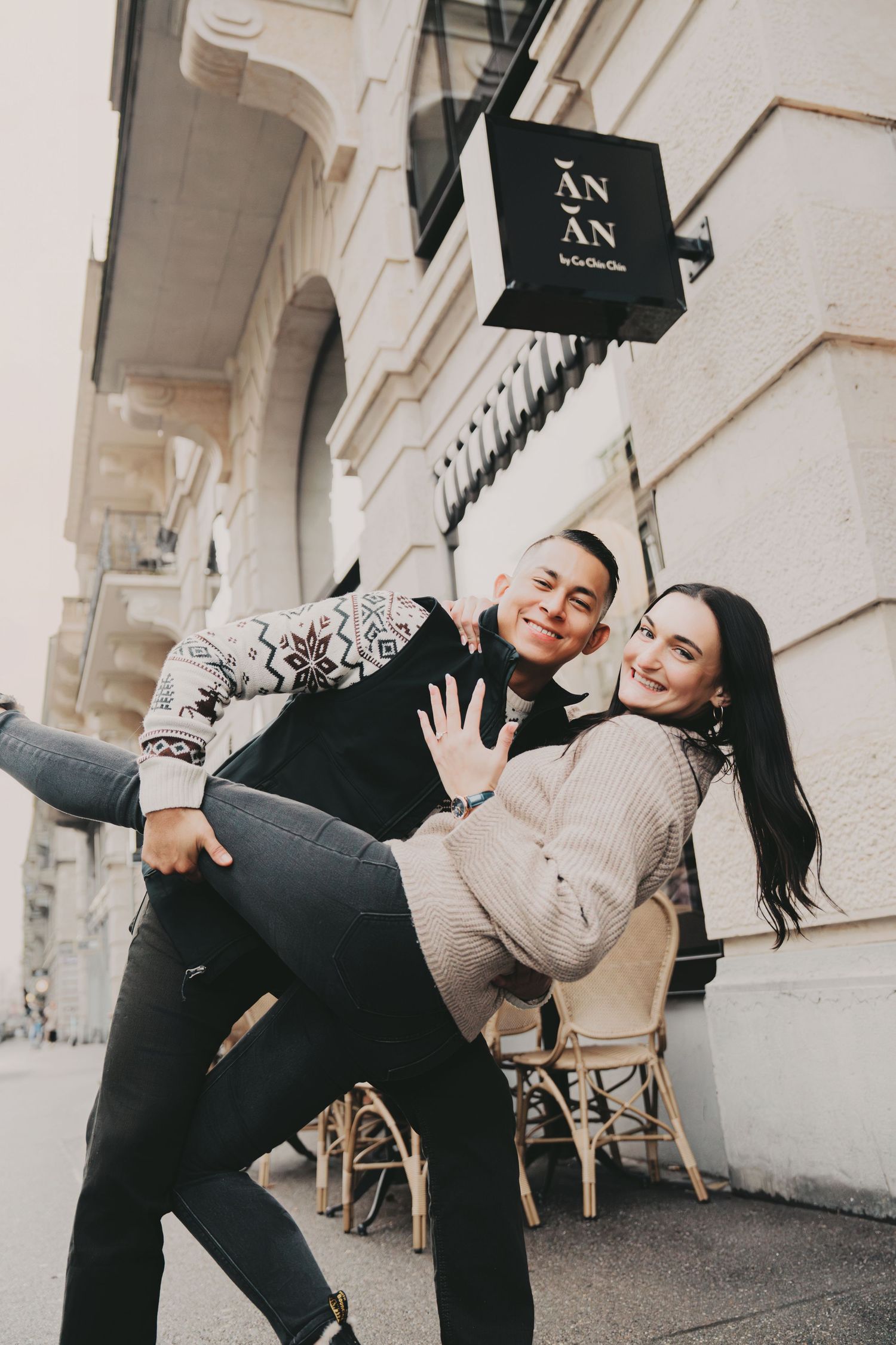 Playful couple posing and laughing outside AN AN restaurant on a European street.