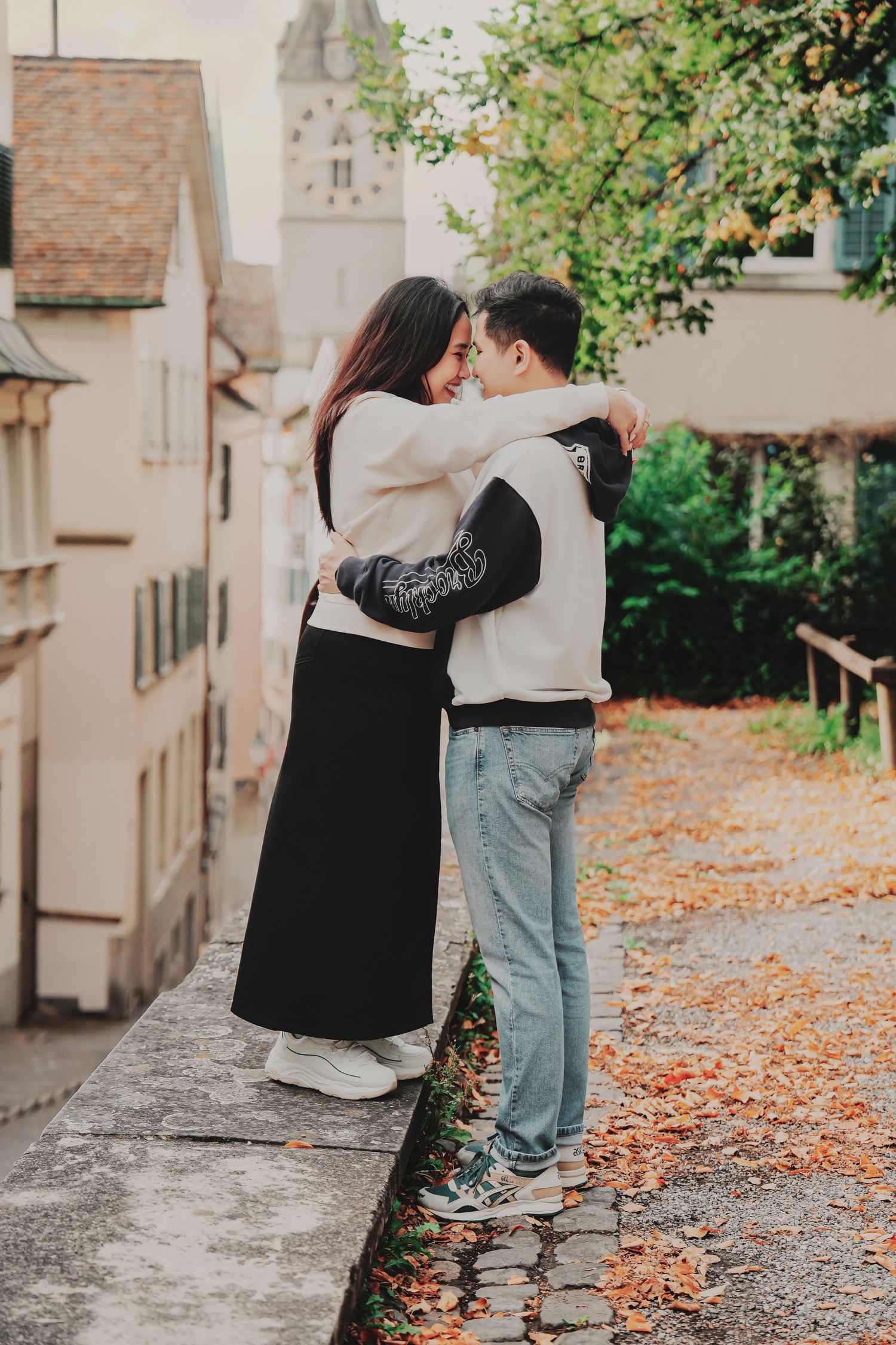 Couple embracing face-to-face on an autumn cobblestone street in Zurich's old town with fallen leaves.