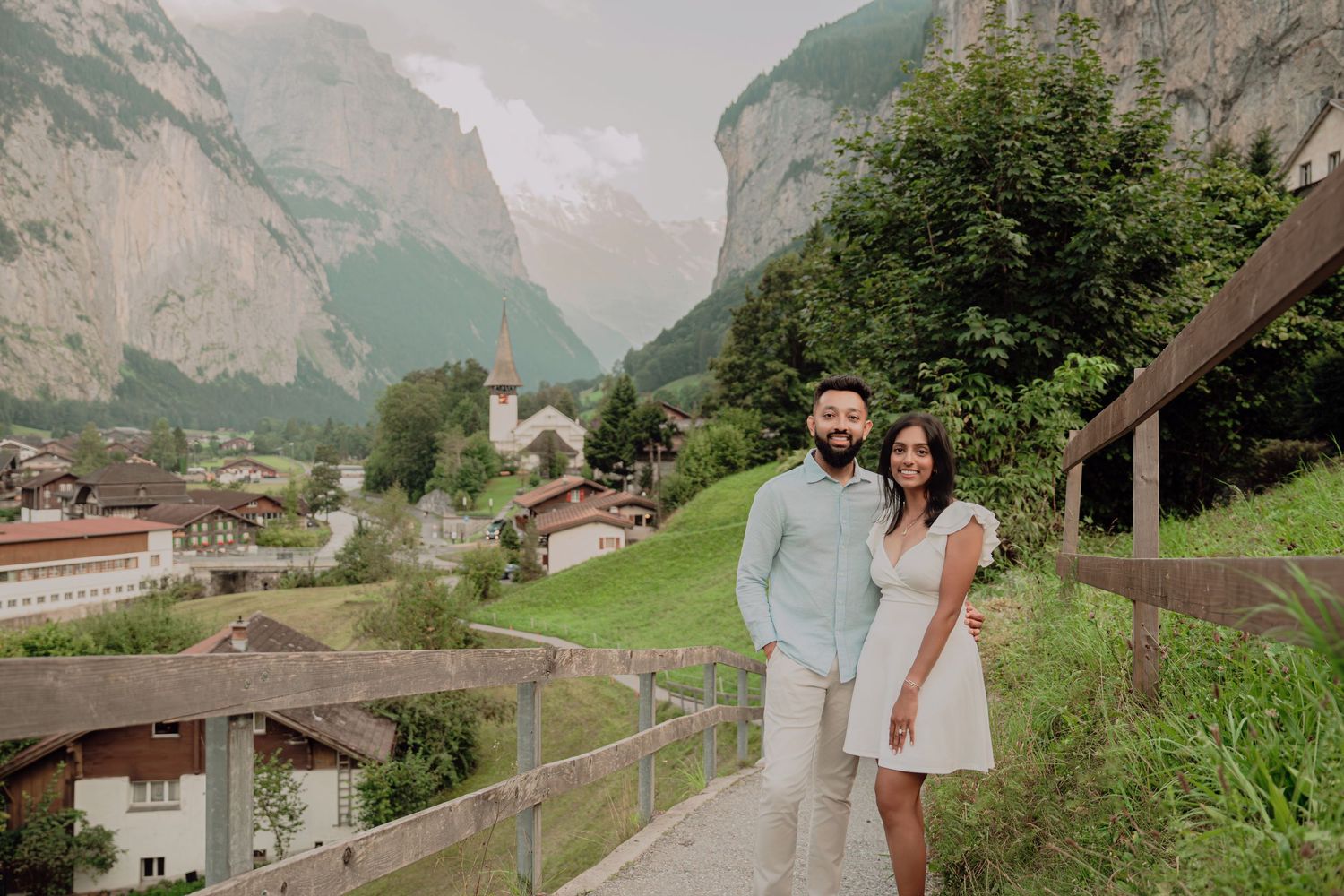 Couple posing together on a hillside path in Lauterbrunnen village, Switzerland, with stunning mountain valley views.