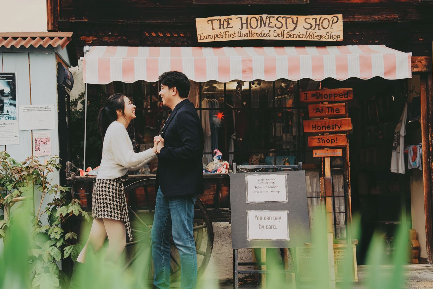 Couple laughing together outside The Honesty Shop vintage store with striped pink awning.