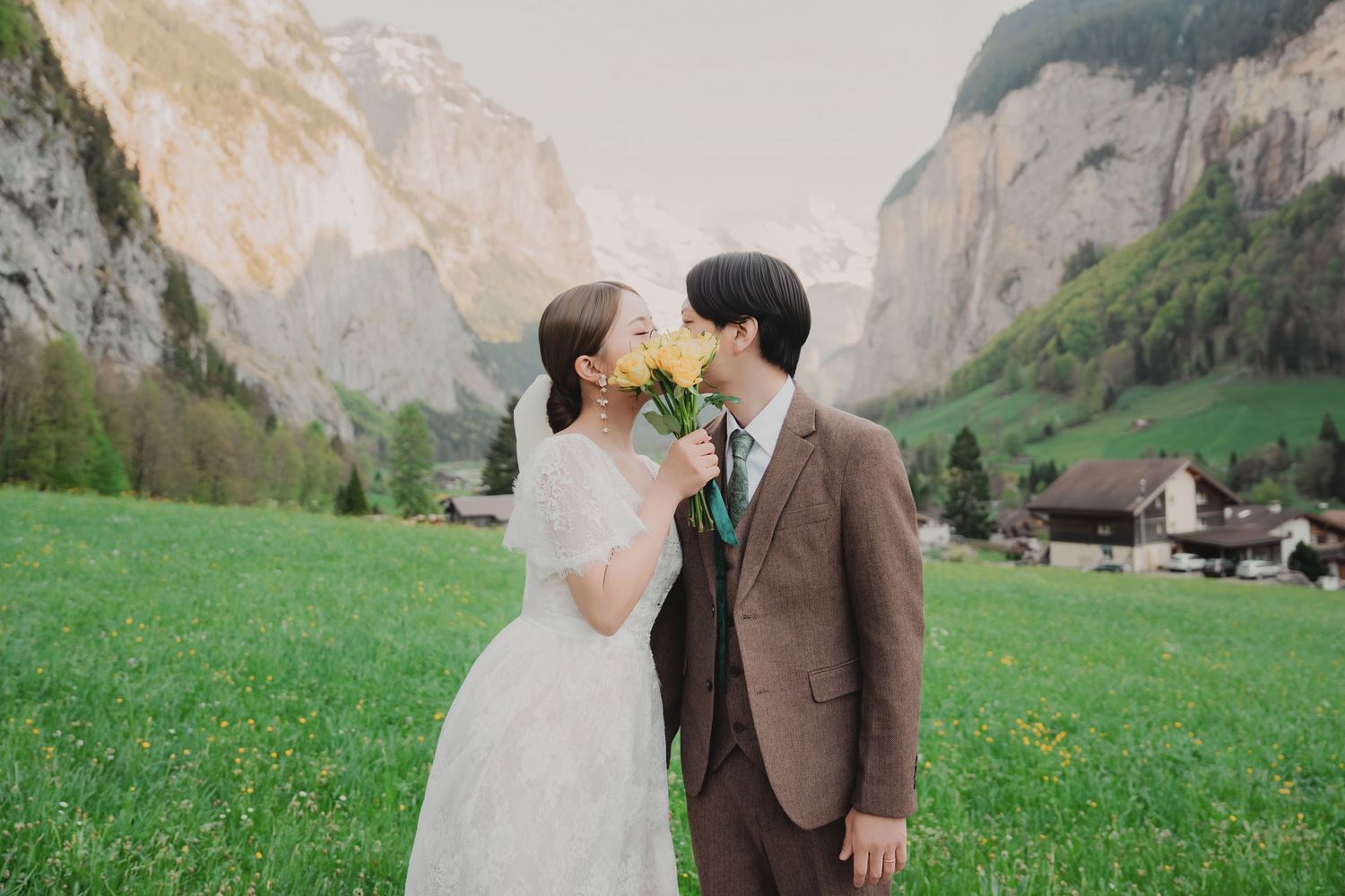 Bride and groom sharing a romantic kiss over a yellow flower bouquet in Swiss Alps.