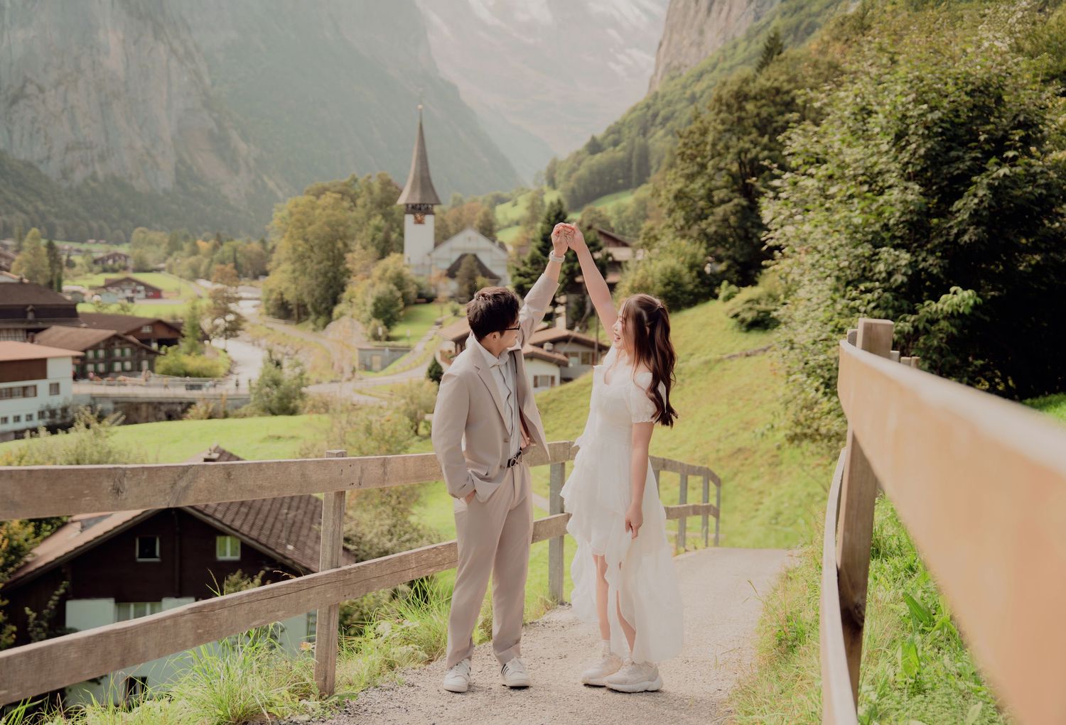 Couple dancing and holding hands on a path in Lauterbrunnen with a charming Swiss village below.