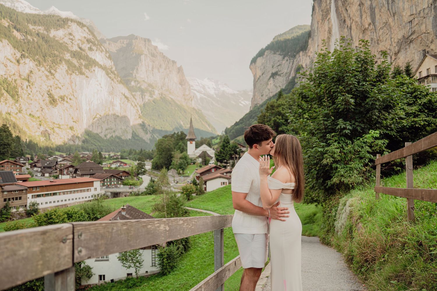 Romantic couple embracing on a scenic overlook path above the charming village of Lauterbrunnen.
