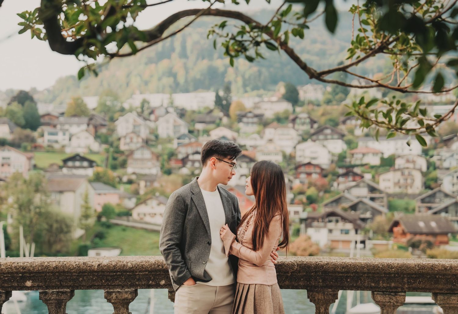 Couple sharing intimate moment on classic stone terrace with scenic European mountain village view.