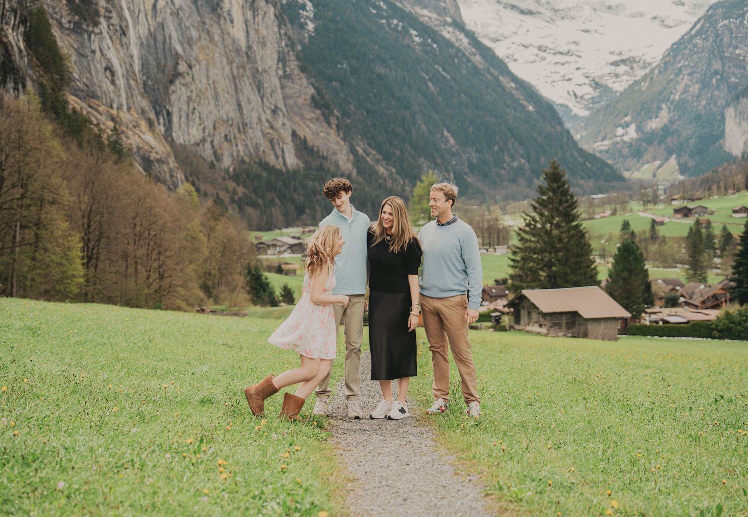 Joyful family walking on path in Lauterbrunnen Switzerland surrounded by mountains and green fields.