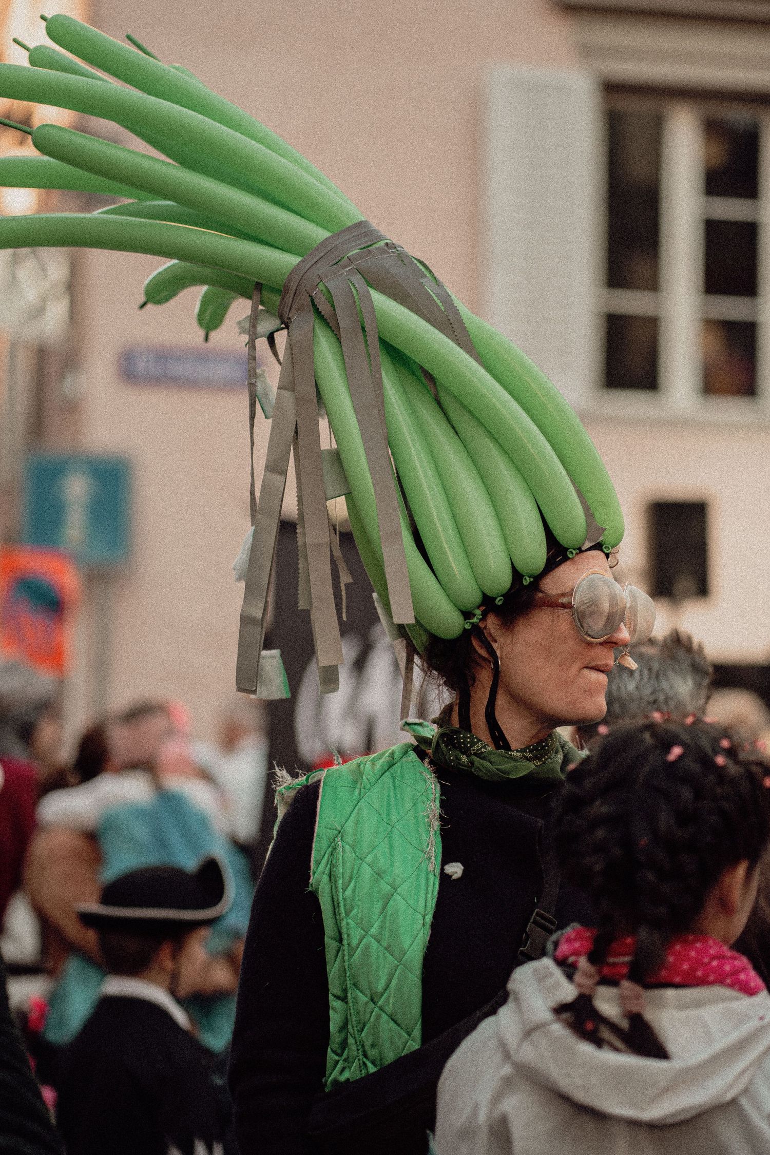Woman wearing a creative costume with green leek vegetables on her head at a carnival.