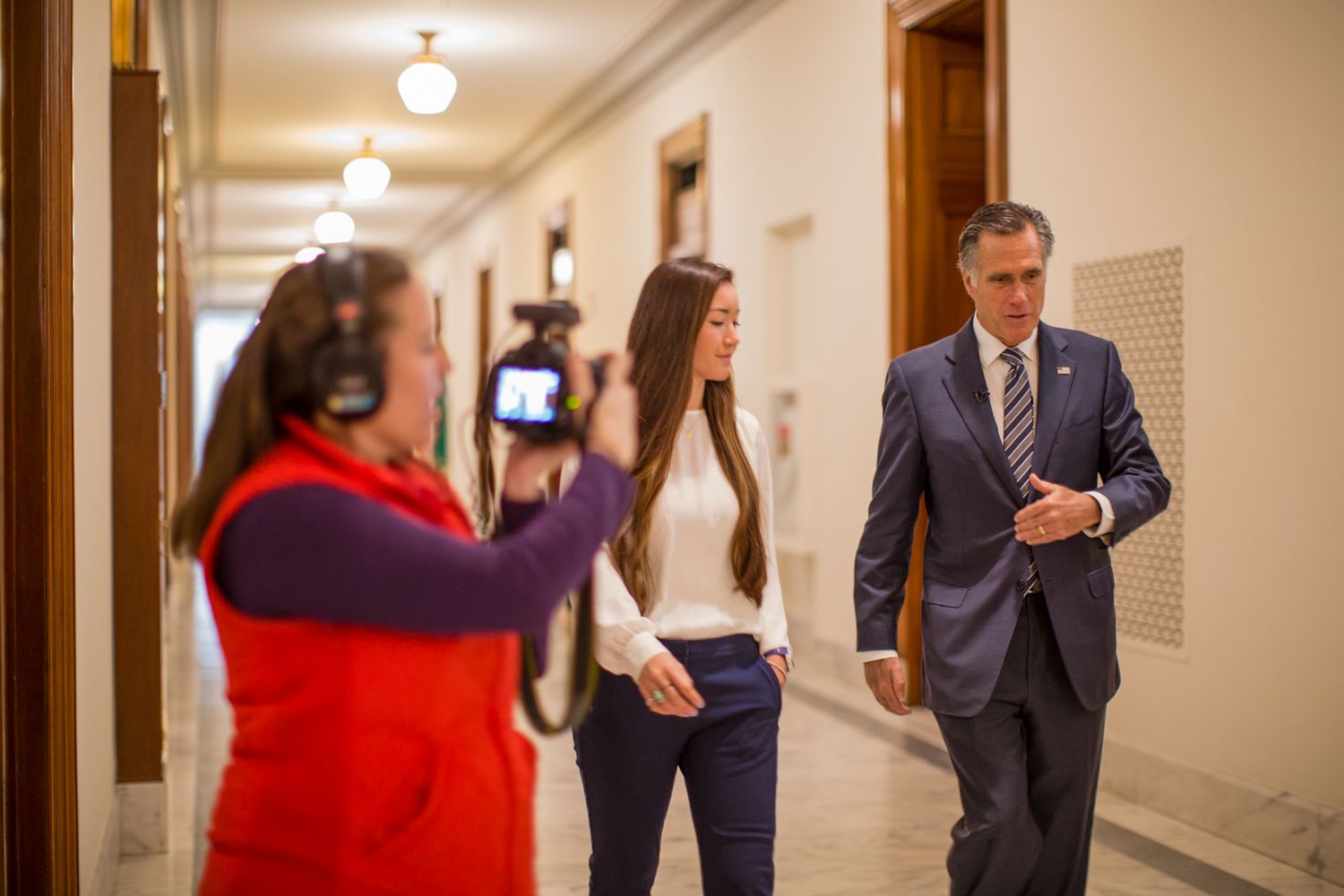 Professional filming taking place in an elegant hallway with overhead lighting.