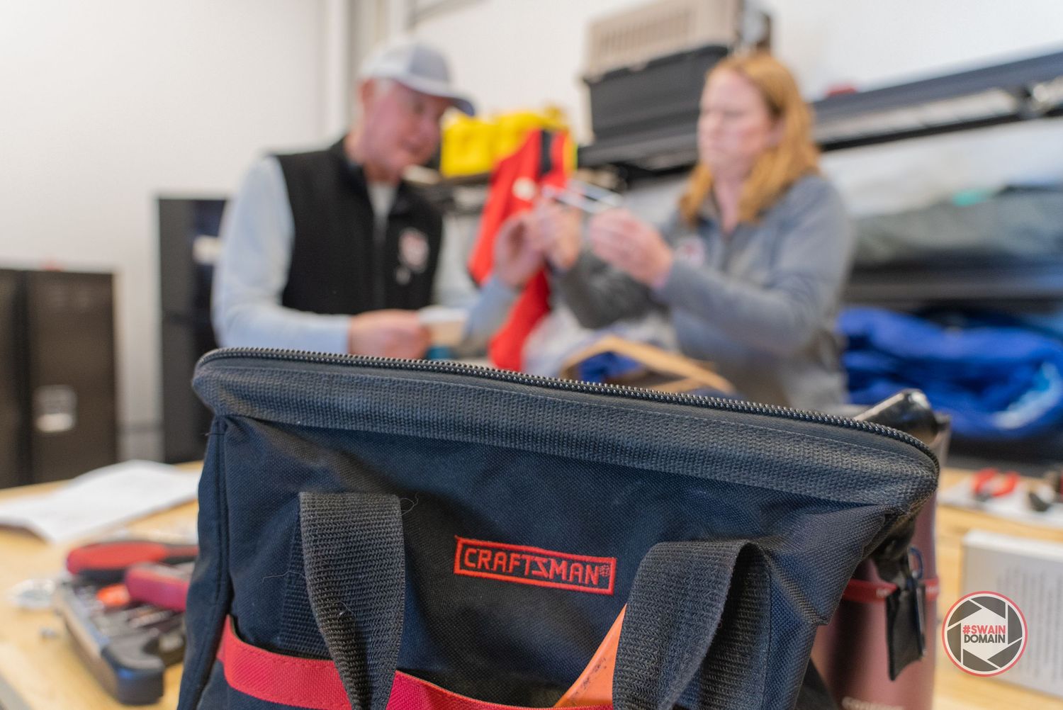A close-up view of a black laptop bag with red accents and compartments being unzipped.