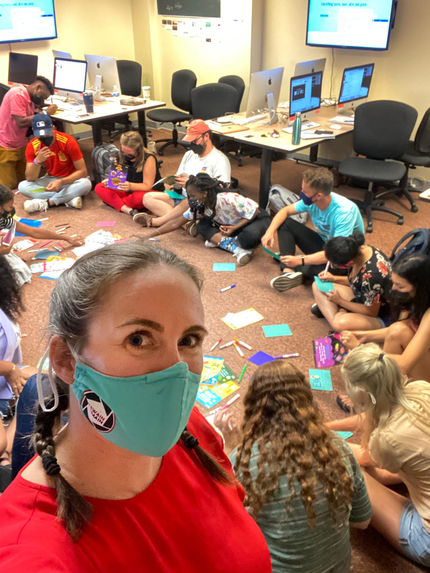 Students working together in a computer lab classroom wearing protective face masks.