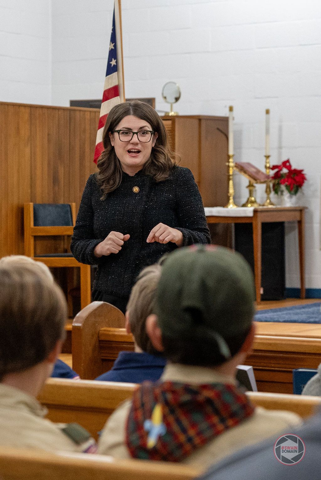 Speaker presents to an audience in a church or community hall setting.