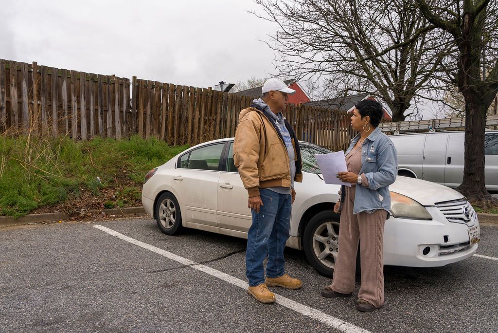 People standing near parked cars in an outdoor lot.