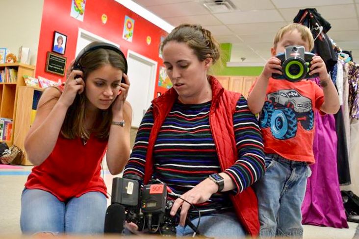 Photography students working together in a classroom with cameras and equipment.
