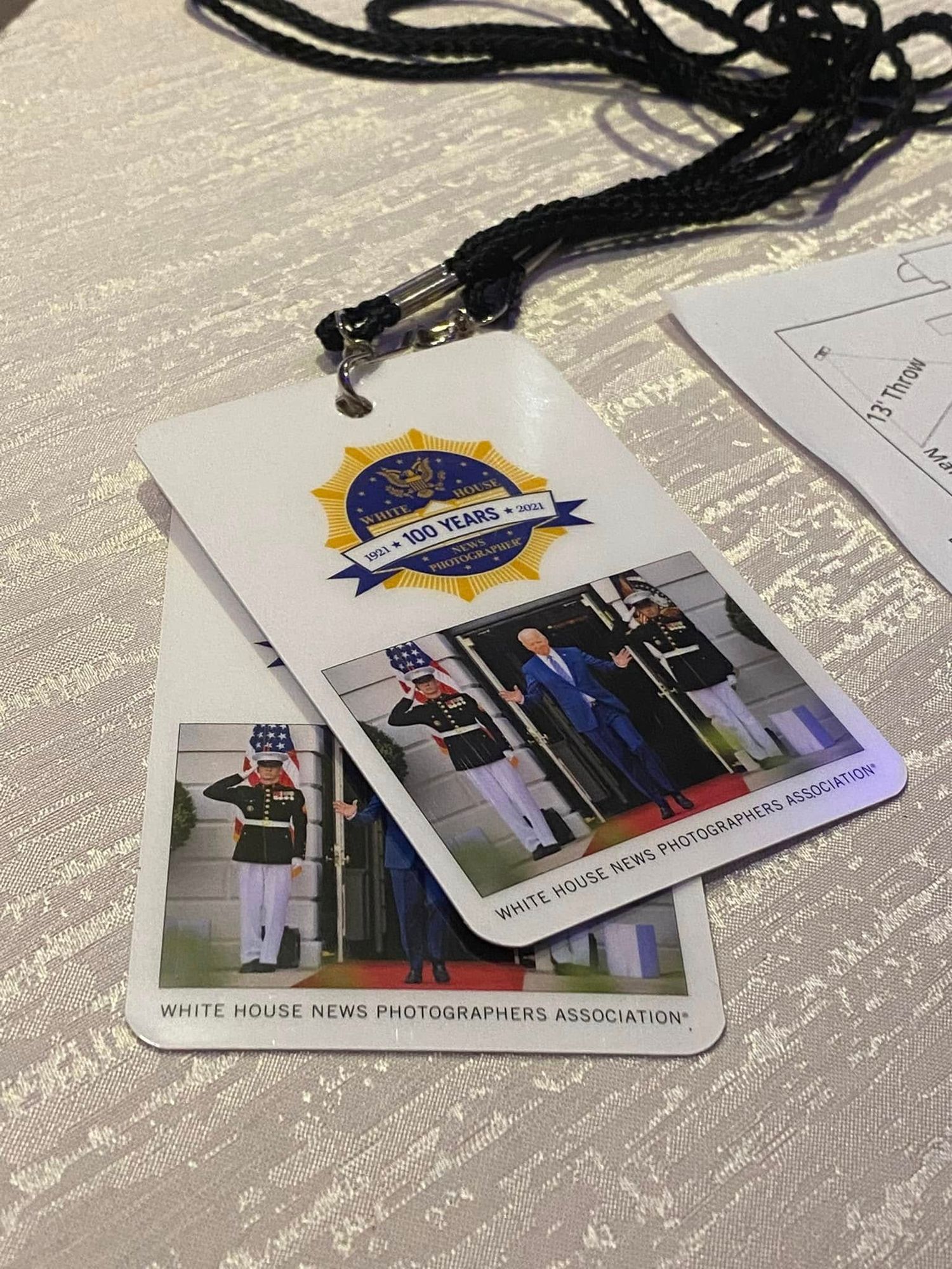 White House News Photographers Association 100th anniversary press credentials badge on a lanyard at an official event.