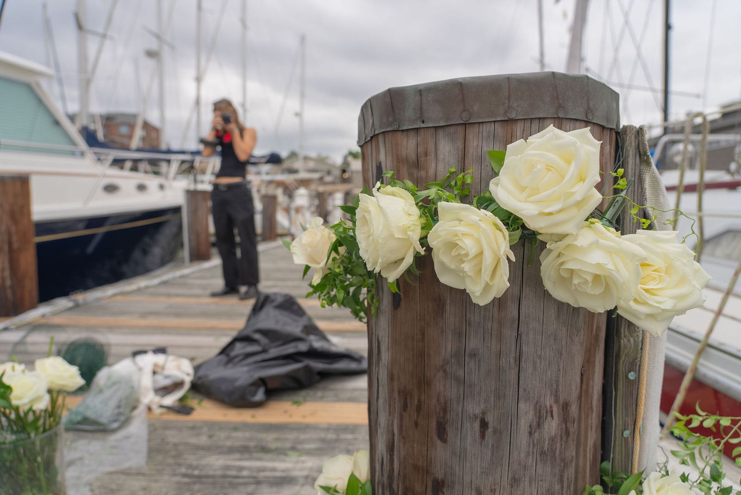 White roses and floral arrangements decorate an outdoor wedding venue setup.