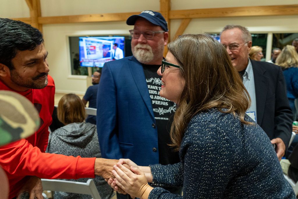 Indoor campaign event with supporters and staff gathered around displays.