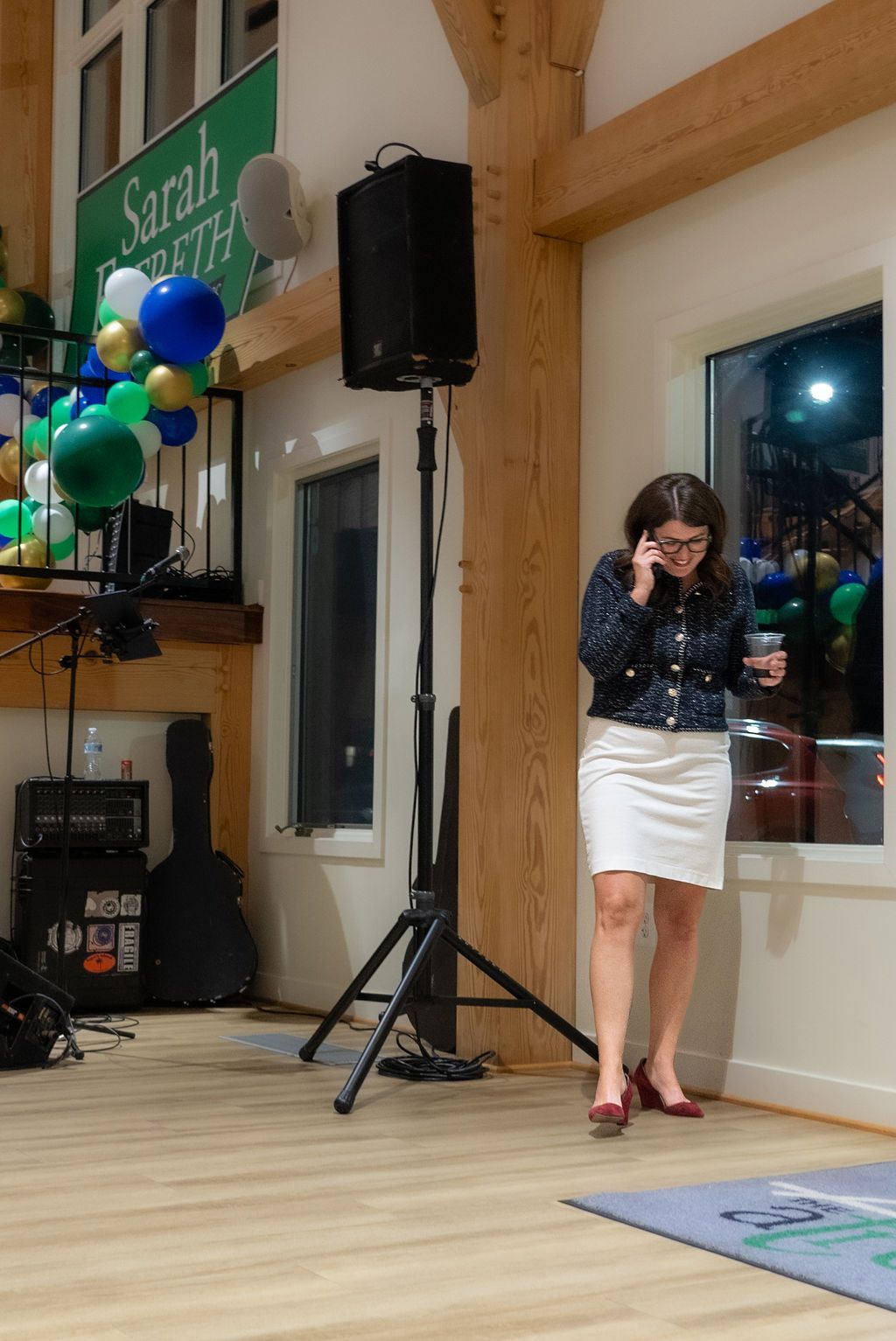 Campaign event space decorated with green signs and blue balloons on wooden floors.